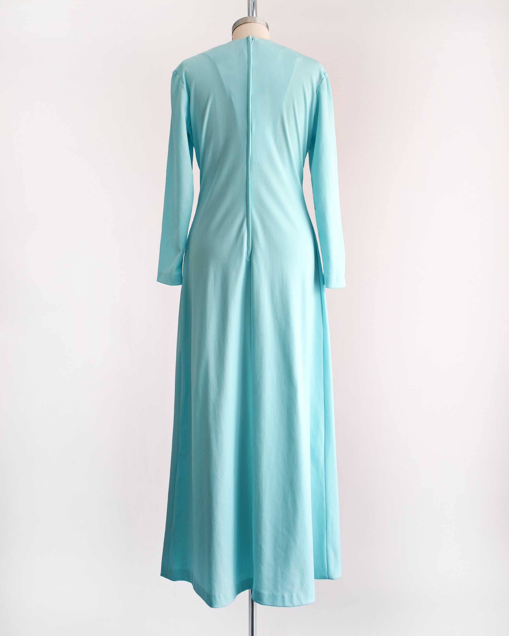 back view of a vintage 1970s light blue maxi dress that has rhinestones on the bodice, a plunging v-neckline, and long sleeves