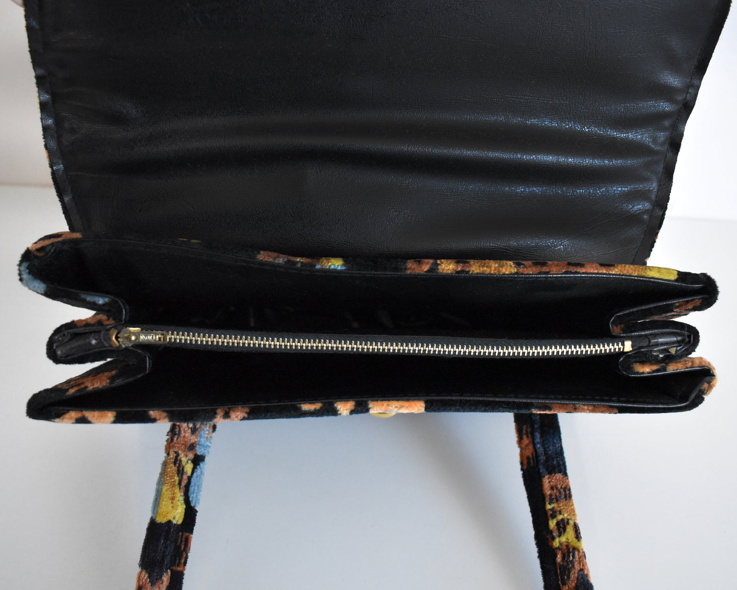 An interior shot of the purse, which is black and features three pockets, one which is zippered.