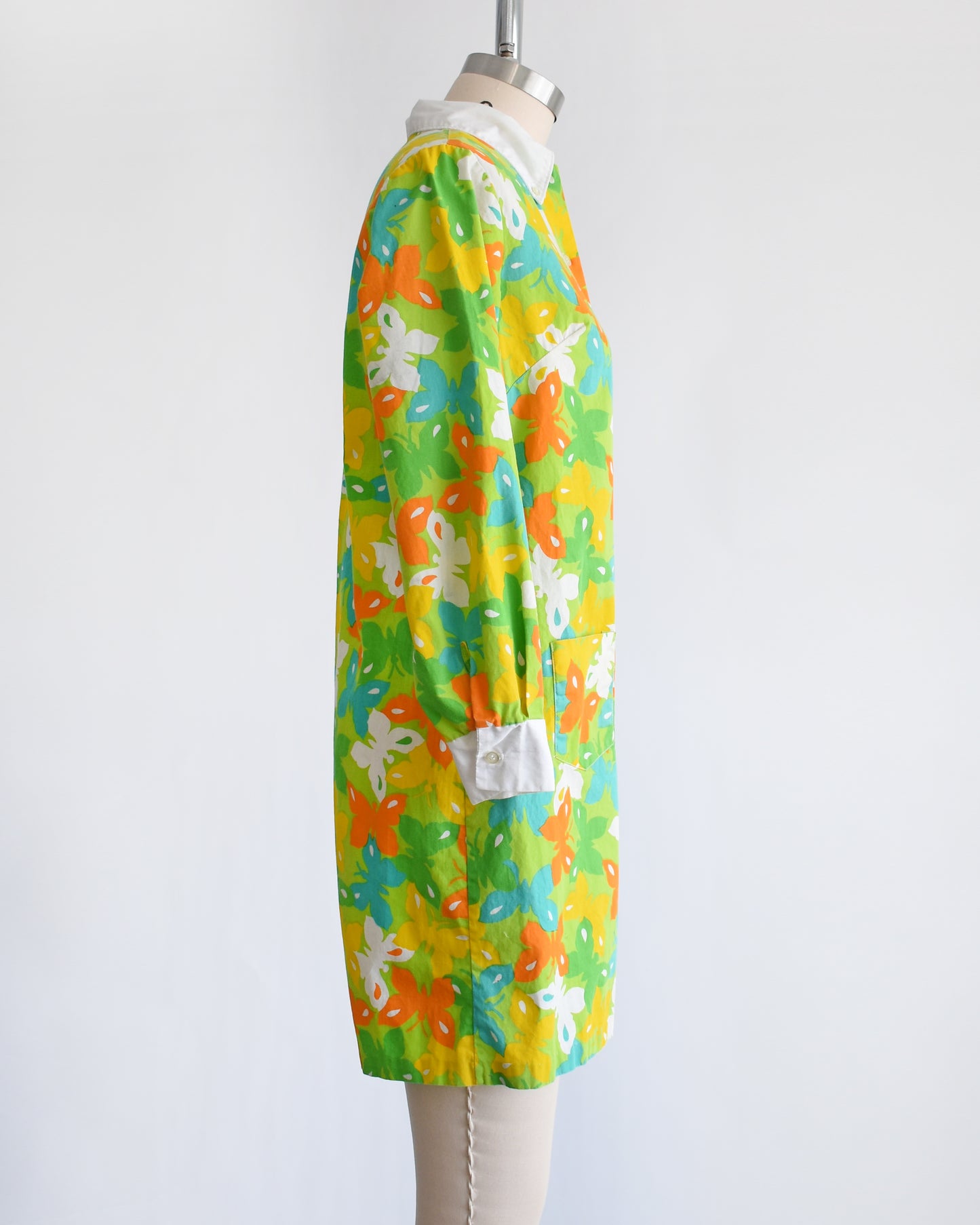 side view of a vintage 1960s green long sleeve romper with multicolored butterfly print all over