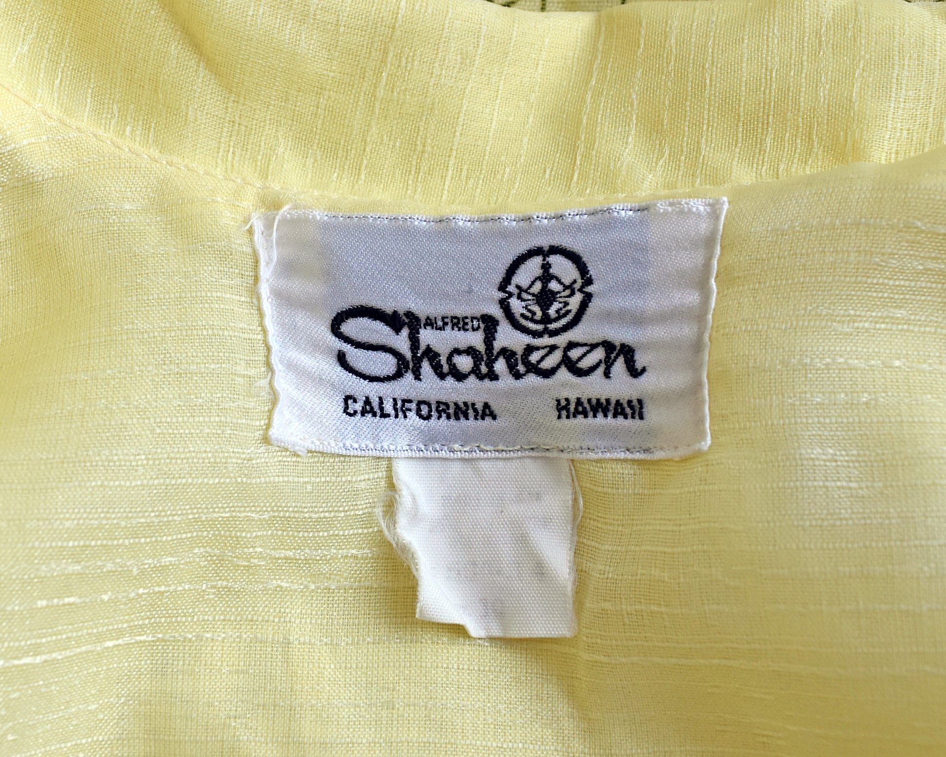 Close up of tag which says Alfred Shaheen, California Hawaii