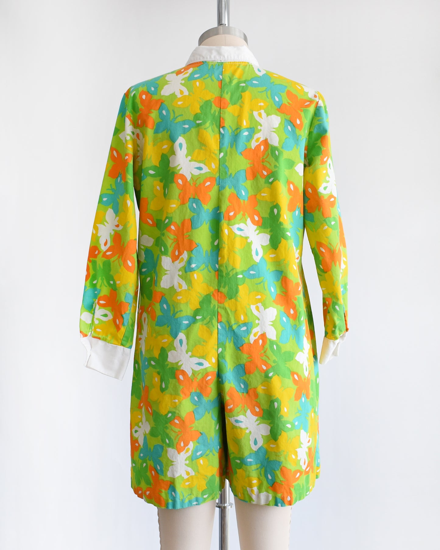back view of a vintage 1960s green long sleeve romper with multicolored butterfly print all over