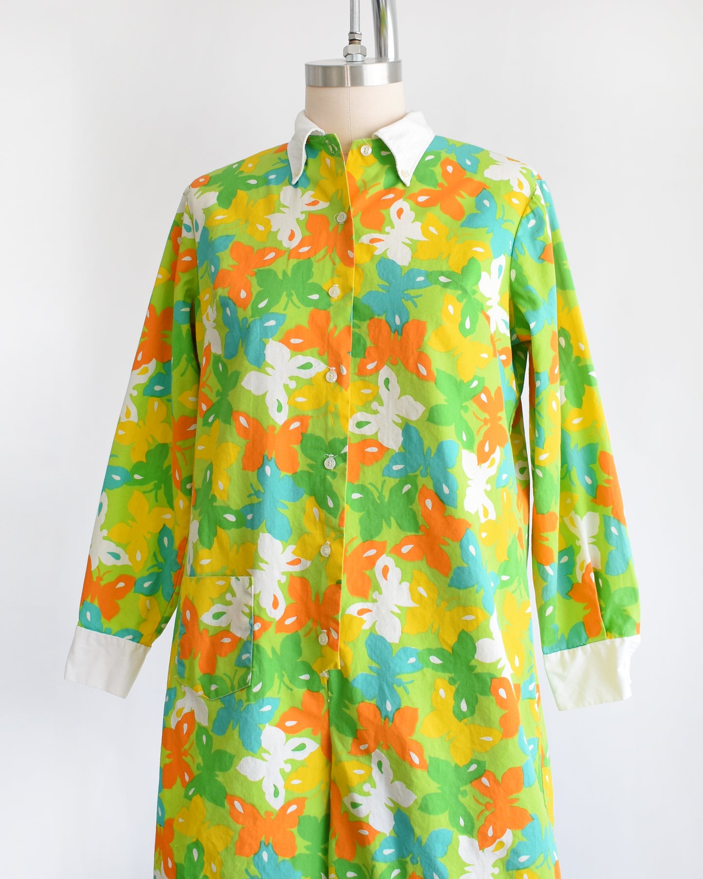 side front view of a vintage 1960s green long sleeve romper with multicolored butterfly print all over