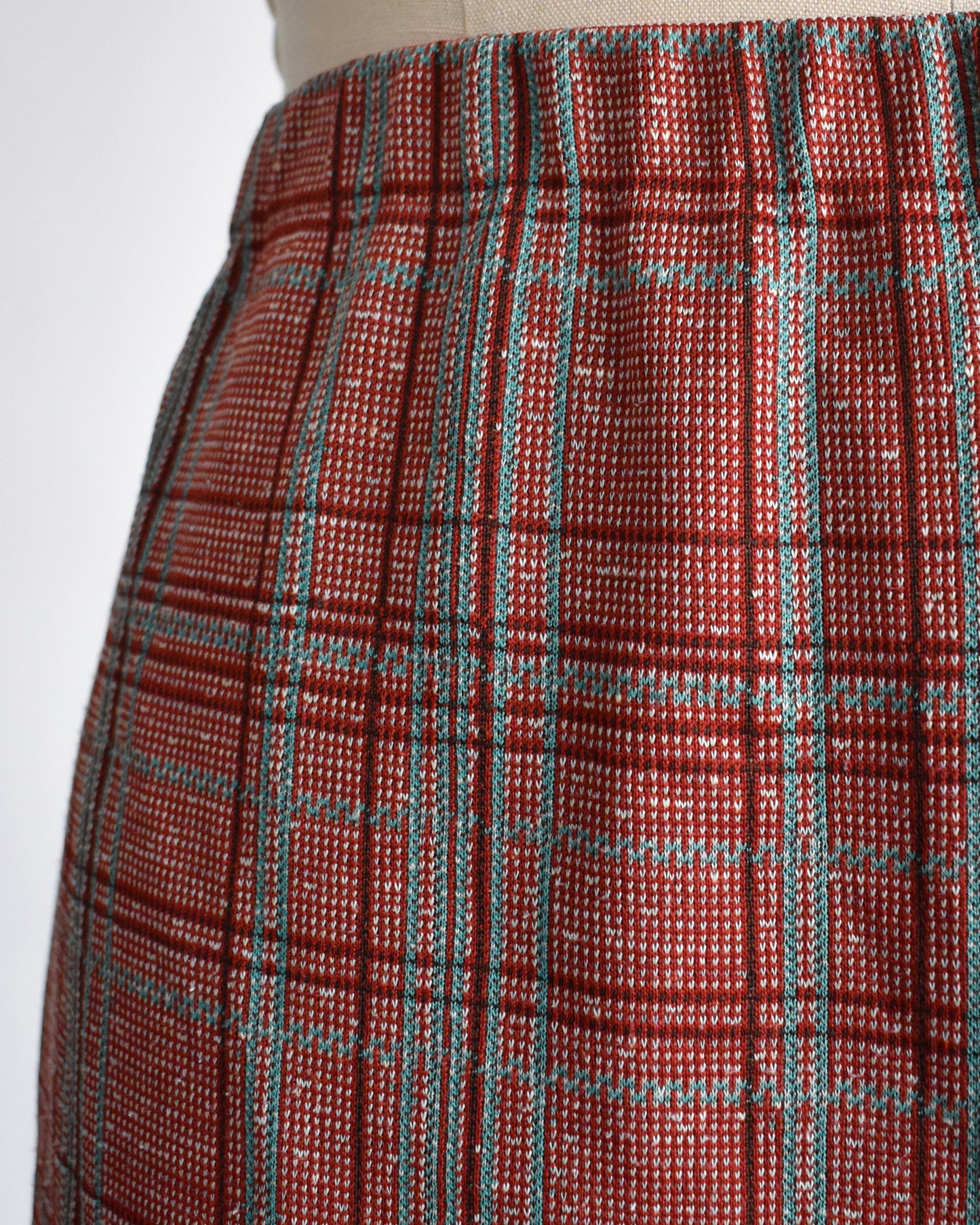 Close-up of a red plaid pants on a mannequin against a white background