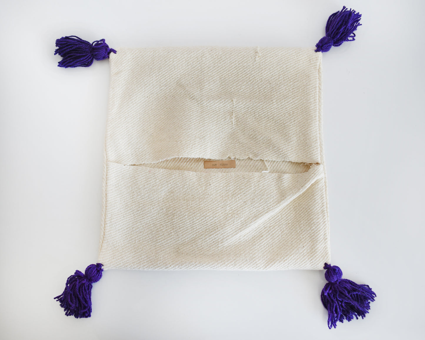 The back of a purple tassel pillow cover showing the opening.