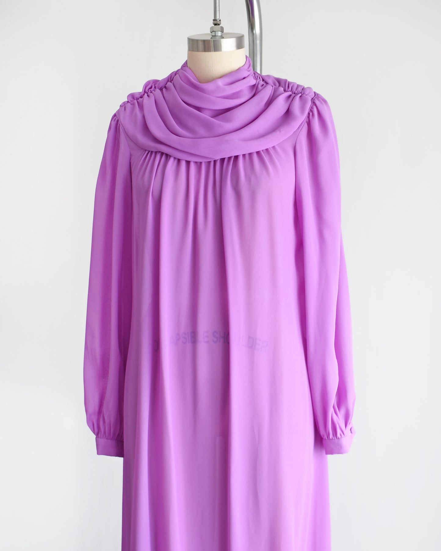 side front view of a vintage 1970s purple semi sheer maxi dress by Joy Stevens California that has a draped neckline and long sleeves