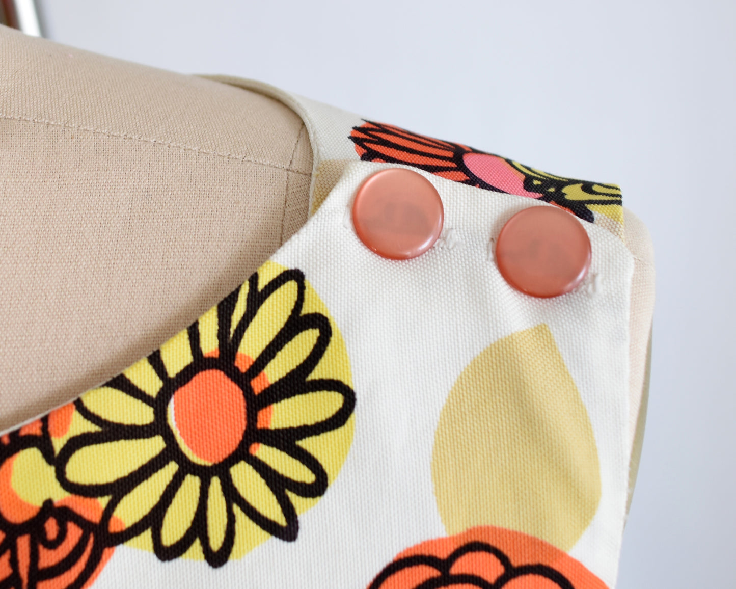 close up of the decorative buttons on the shoulder of a vintage 1960s flower power shift dress