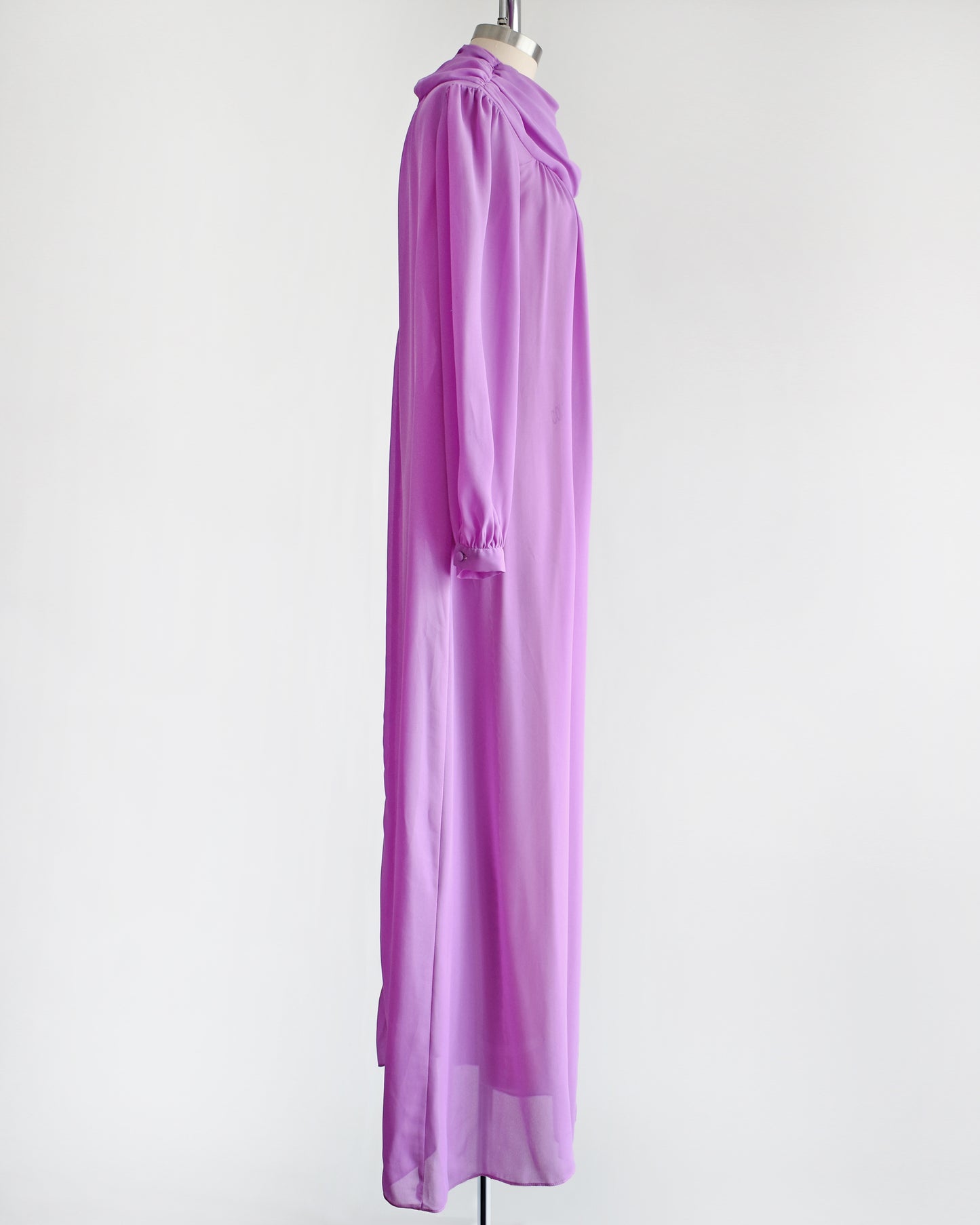 Side view of a vintage 1970s purple semi sheer maxi dress by Joy Stevens California that has a draped neckline and long sleeves