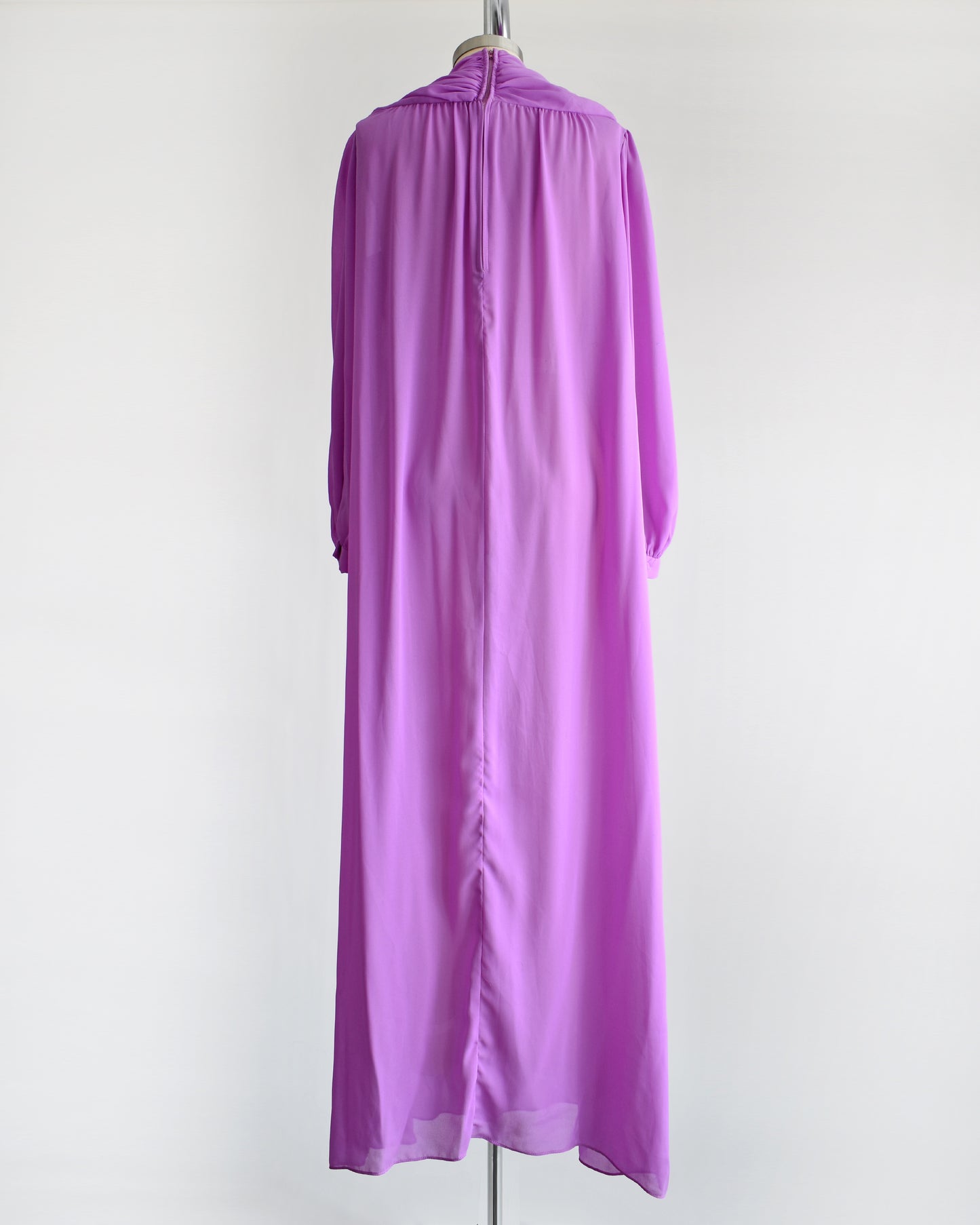 back view of a vintage 1970s purple semi sheer maxi dress by Joy Stevens California that has a draped neckline and long sleeves