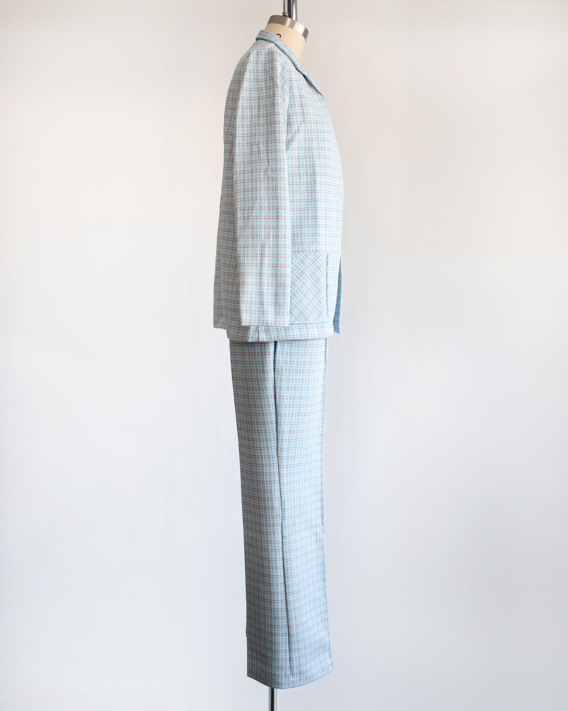 Side view of a  vintage 1970s blue, white, and orange plaid pantsuit. This set includes a blazer and matching wide leg pants.