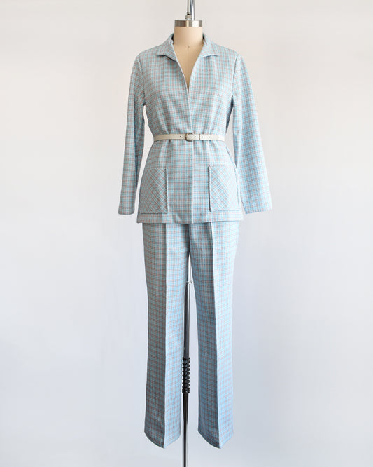 A  vintage 1970s blue, white, and orange plaid pantsuit. This set includes a blazer and matching wide leg pants. The piece is modeled with a white belt which isn't included.