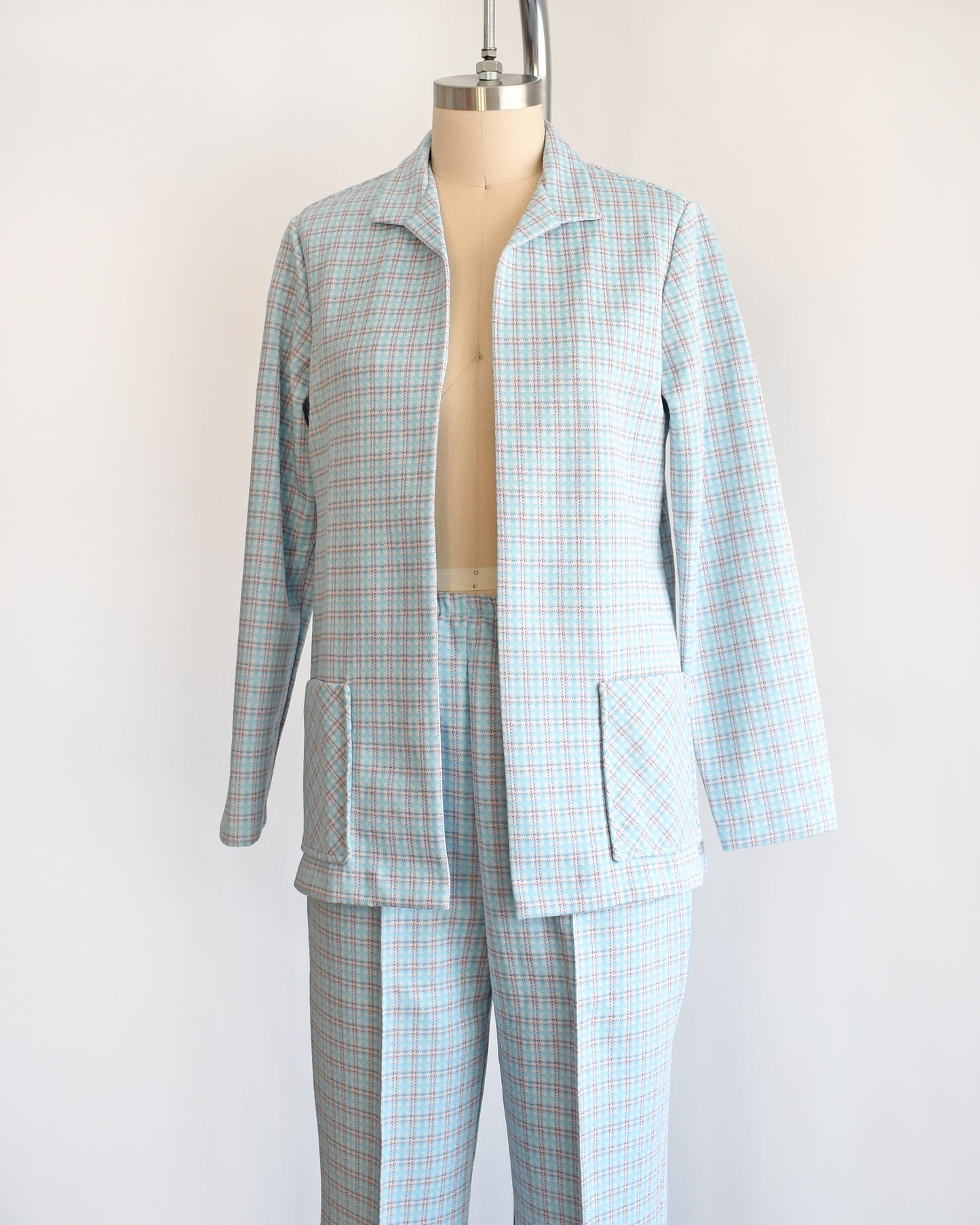 Side front view of a  vintage 1970s blue, white, and orange plaid pantsuit. This set includes a blazer and matching wide leg pants.