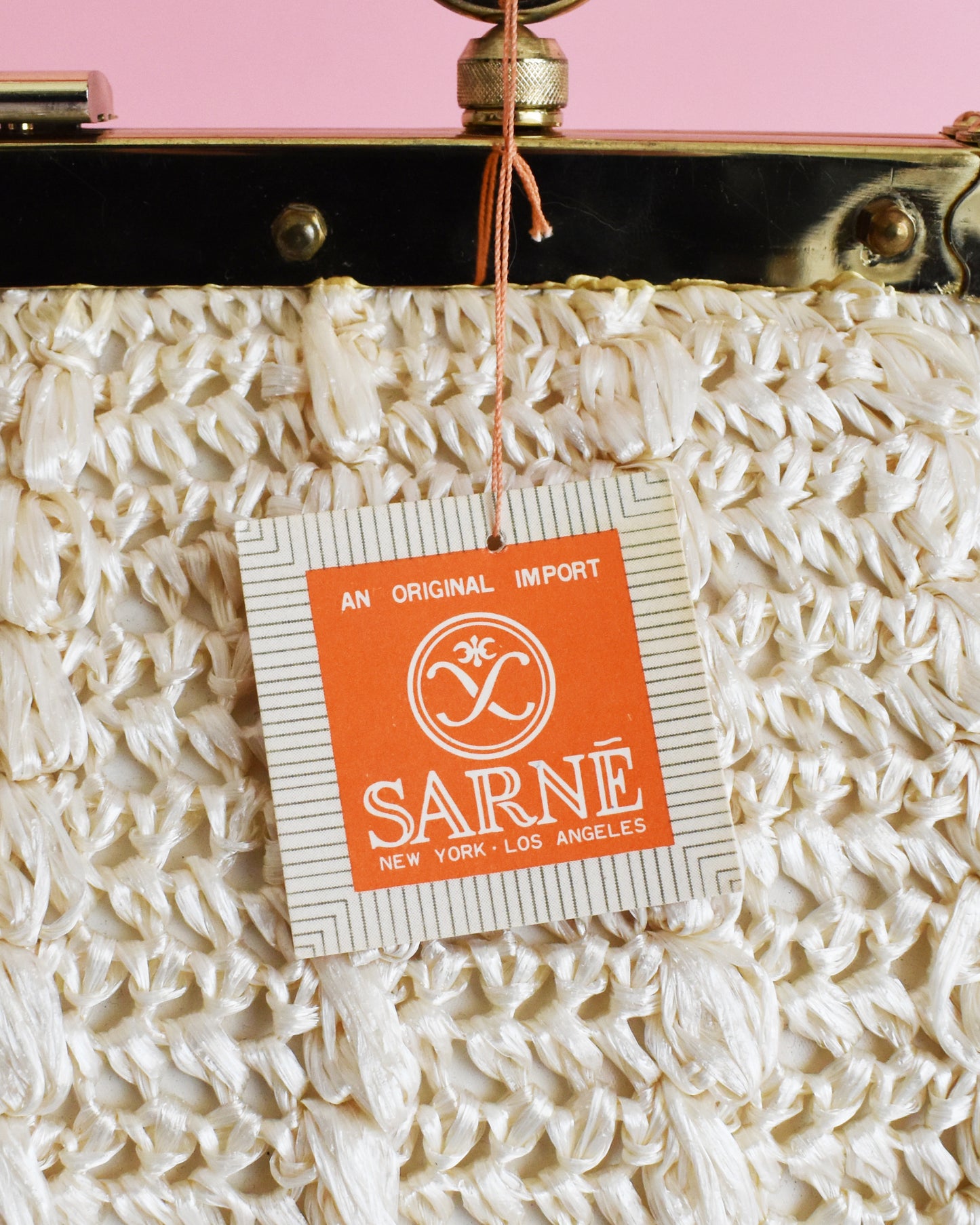 Vintage handbag with a SARNE label tag on a pink background