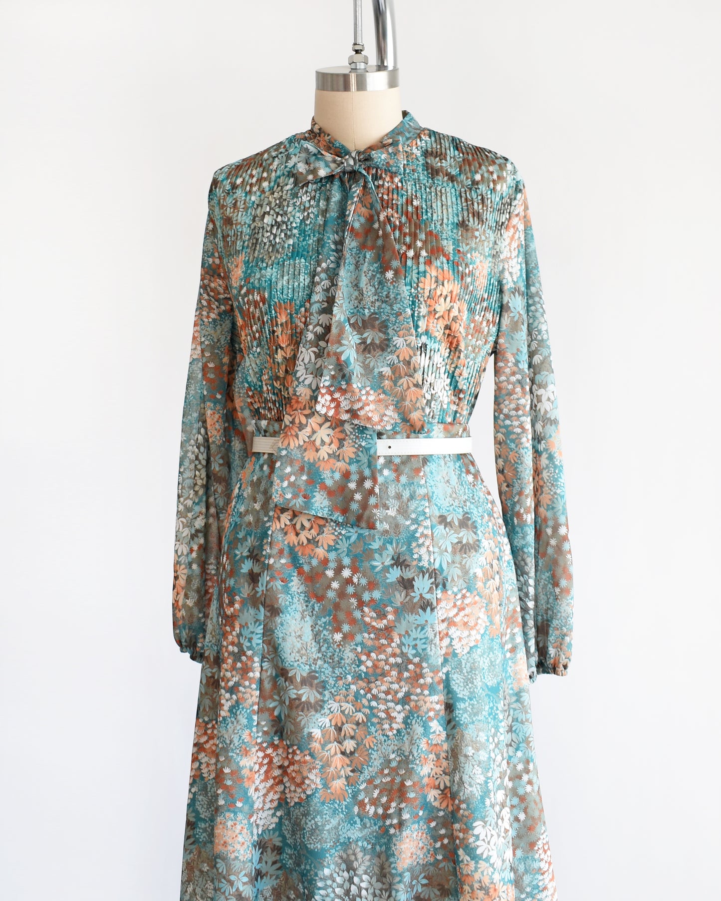 Side front view of a vintage 1970s floral blue and orange floral dress set. This set comes with a matching blouse and skirt. The set is modeled with a white belt that isn't inclued