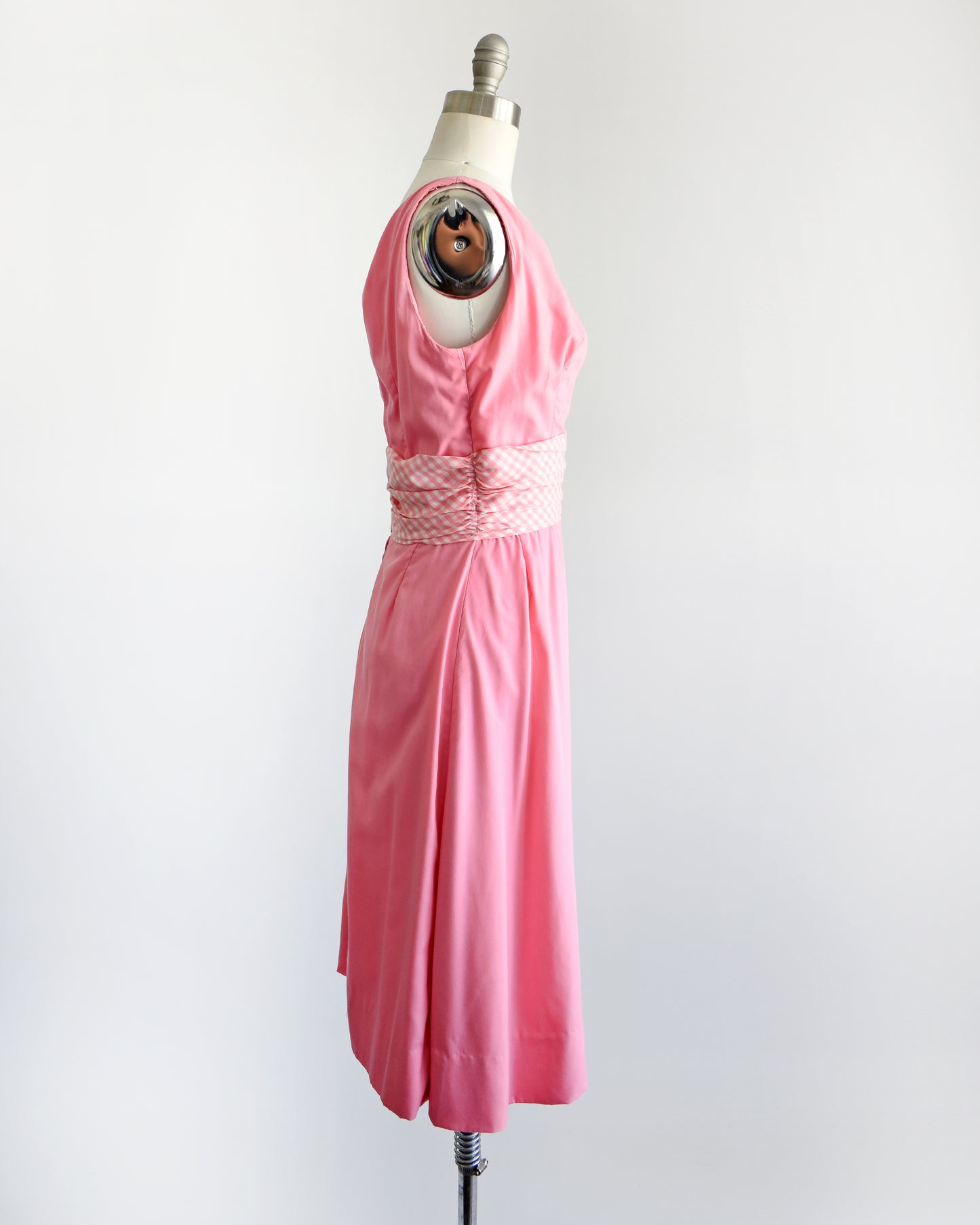 side view of a vintage 1960s pink dress by Gigi Young that has a pink and white gingham waistband