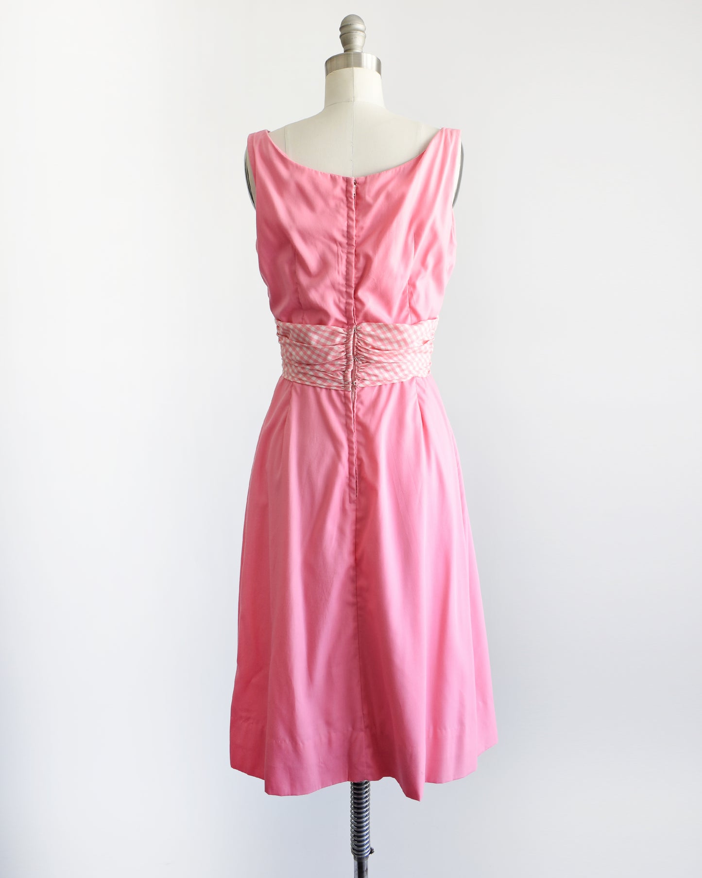 back view of a vintage 1960s pink dress by Gigi Young that has a pink and white gingham waistband
