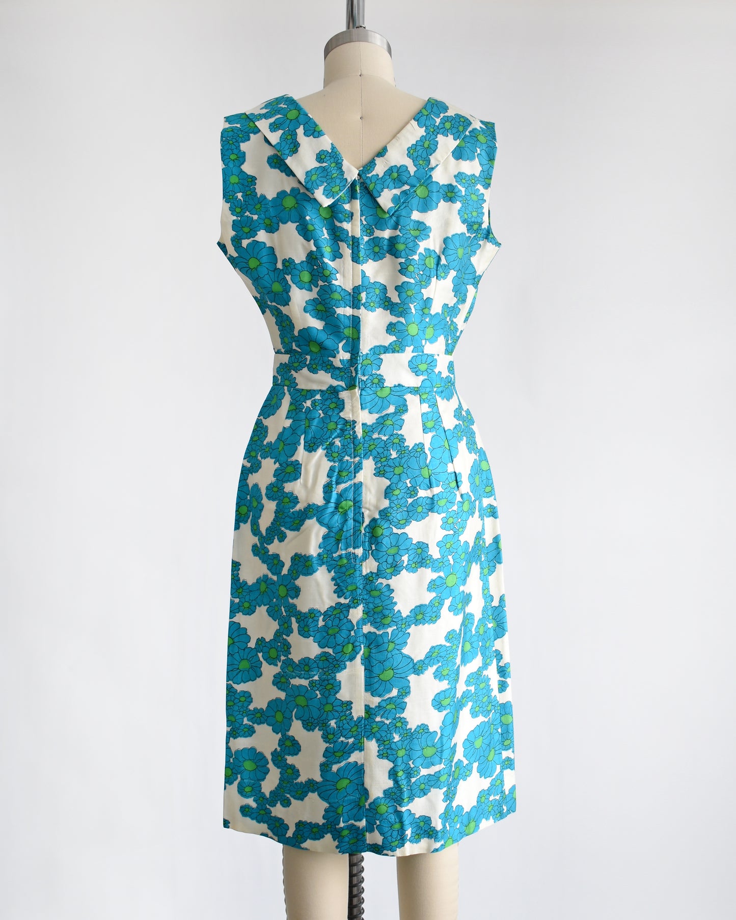 back view of a vintage 1960s blue and white floral dress on a dress form