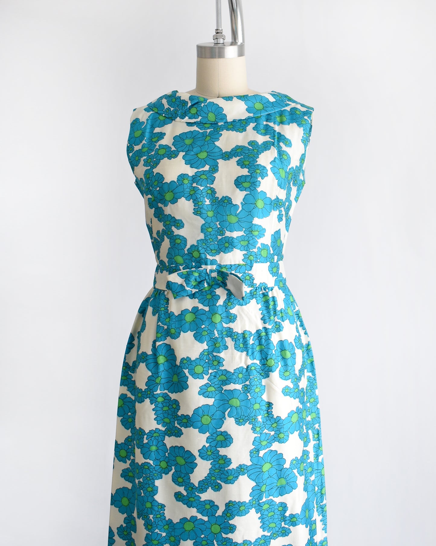 side front view of a vintage 1960s blue and white floral dress on a dress form