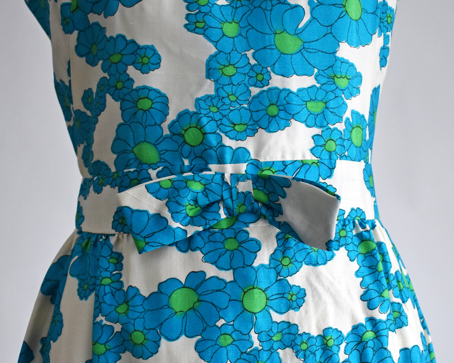 close up of the bow on the waist of a vintage 1960s blue and white floral dress