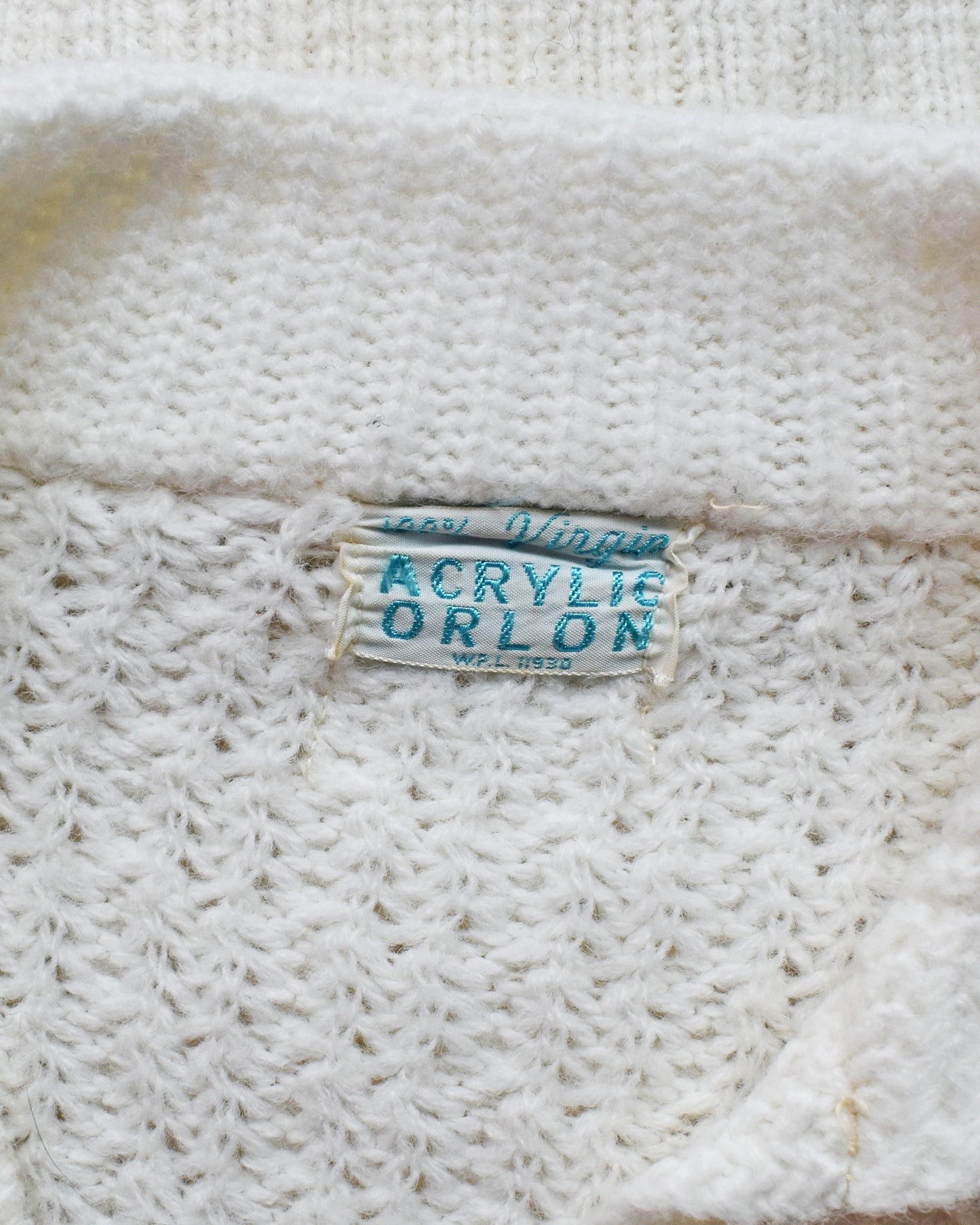 Close-up of a label on a textured white fabric, showing 'Acrylic Orlon' text.