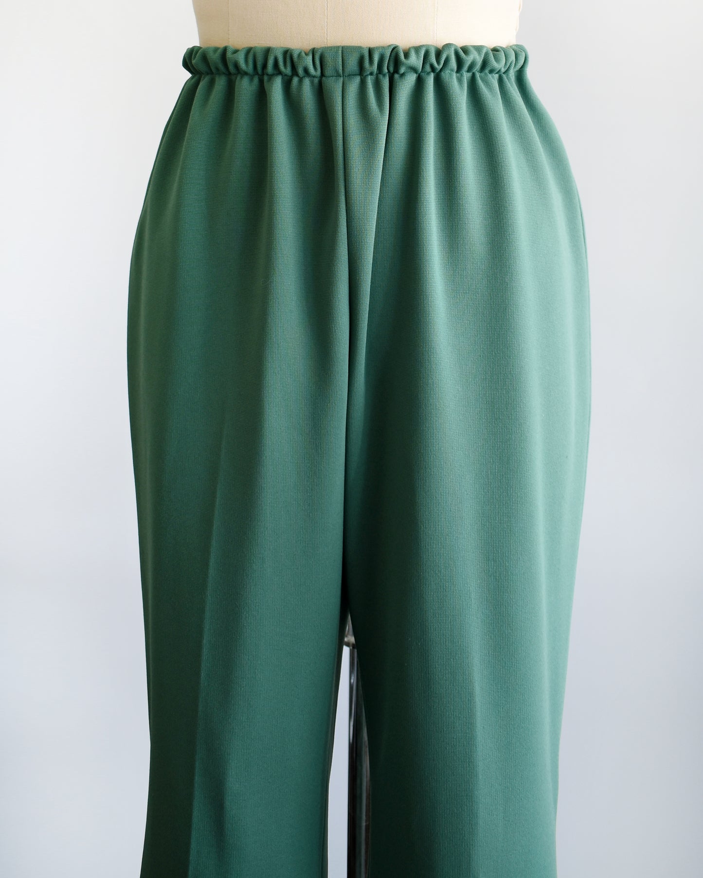 close up view of a pair of vintage 1970s green wide leg pants on a dress form