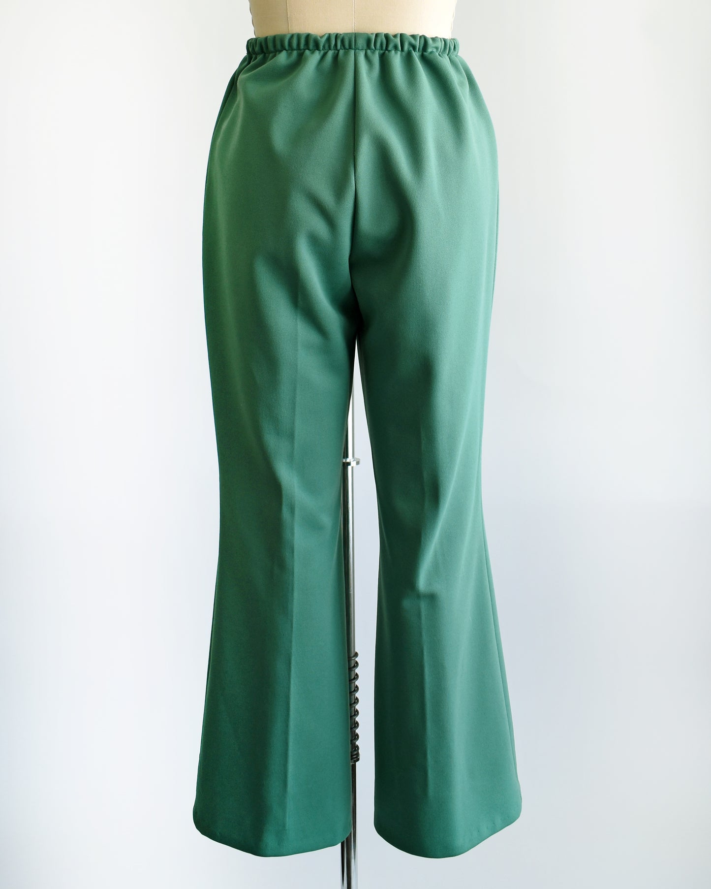 back view of a pair of vintage 1970s green wide leg pants on a dress form