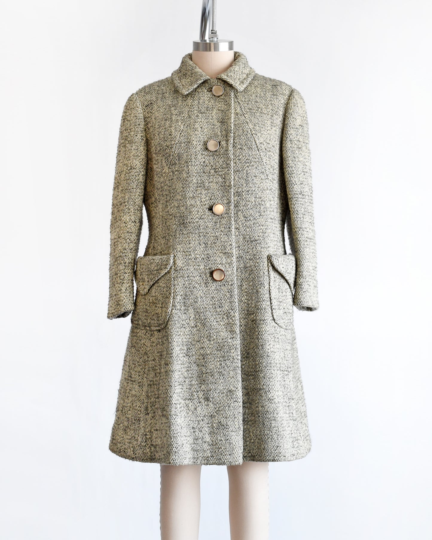 a vintage 1960s gray and cream wool bouclé coat. the buttons are buttoned all the way up.