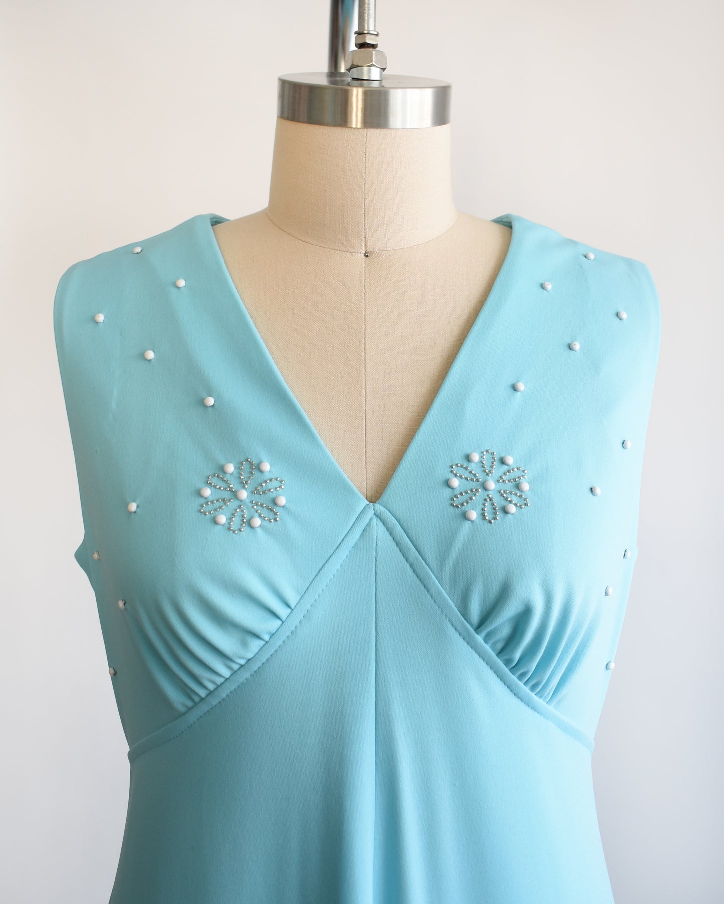 Close up of the bodice, which shows blue and silver beads, with two decorative beaded flowers on each side.