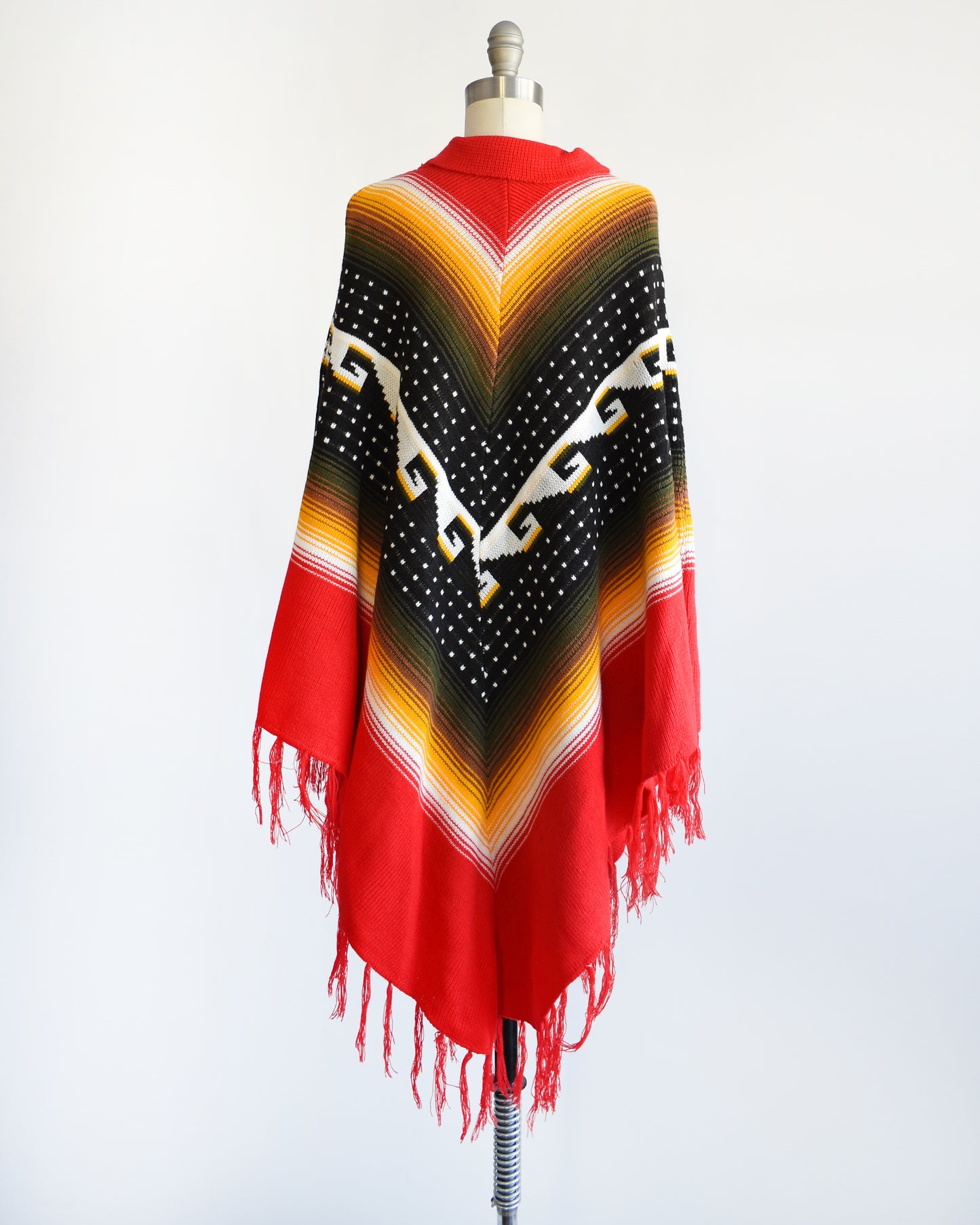 Back view of a vintage 1970s chevron striped fringe poncho that has a folded over red collar with and two tassels that can be tied into a bow.