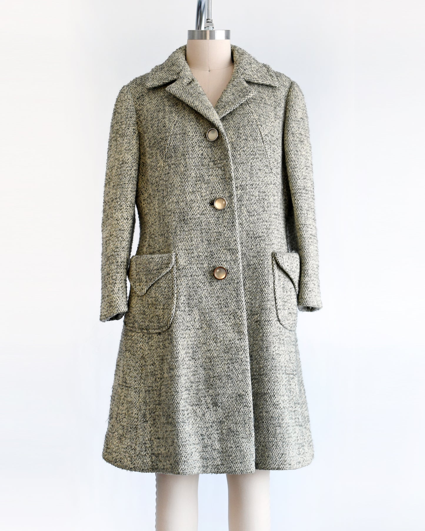 a vintage 1960s gray and cream wool bouclé coat. the top button is unbuttoned