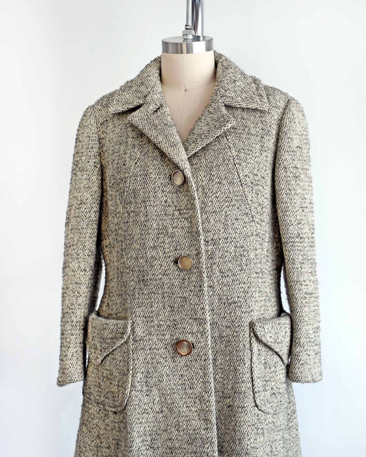 side front view of a vintage 1960s gray and cream wool bouclé coat. the top button is unbuttoned