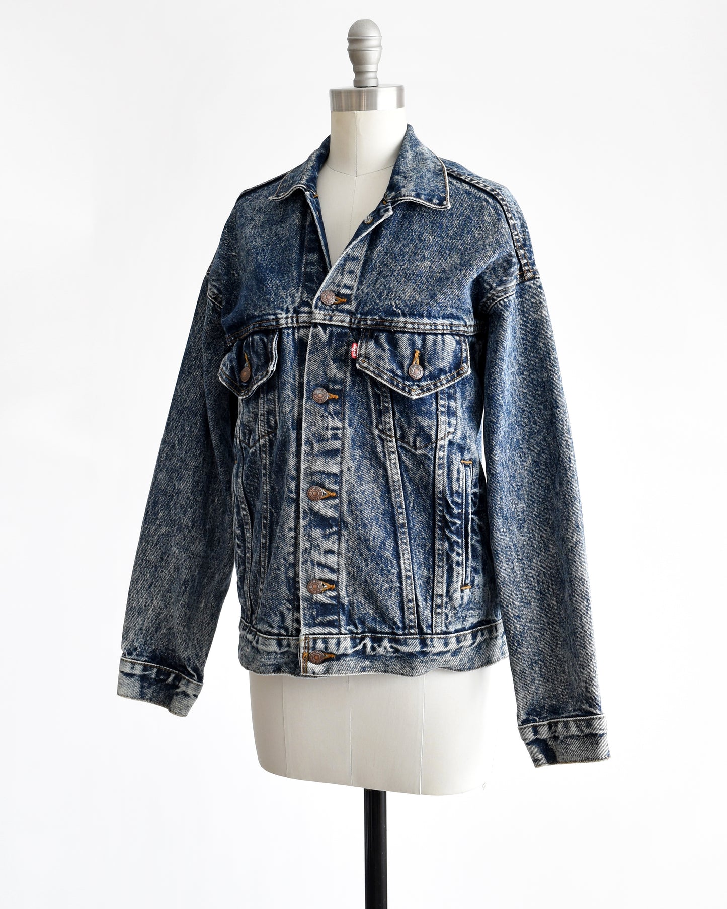 Side front view of a vintage 80s Levis blue jean denim jacket button up on a dress form.