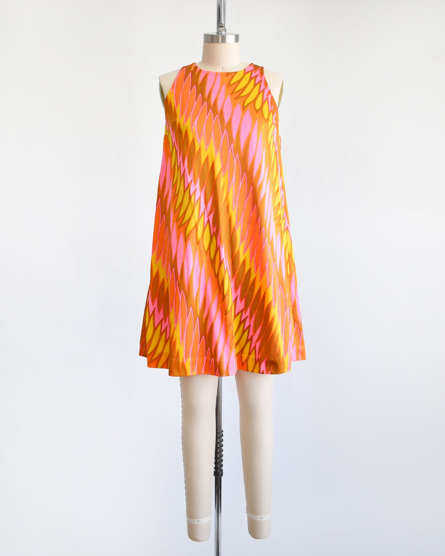 a vintage 1960s mini dress that has a psychedelic print in orange, pink, yellow, and brown
