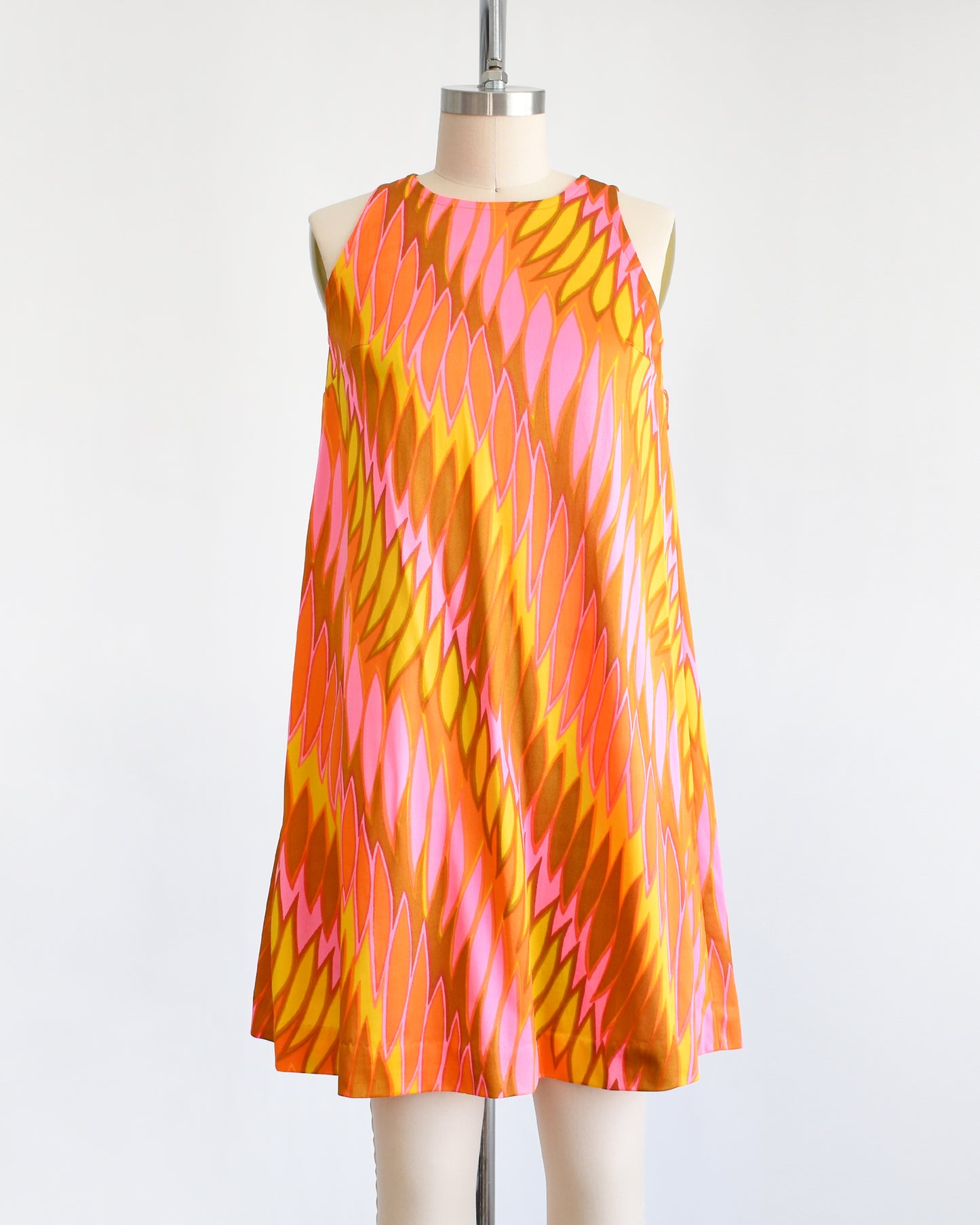 a vintage 1960s mini dress that has a psychedelic print in orange, pink, yellow, and brown