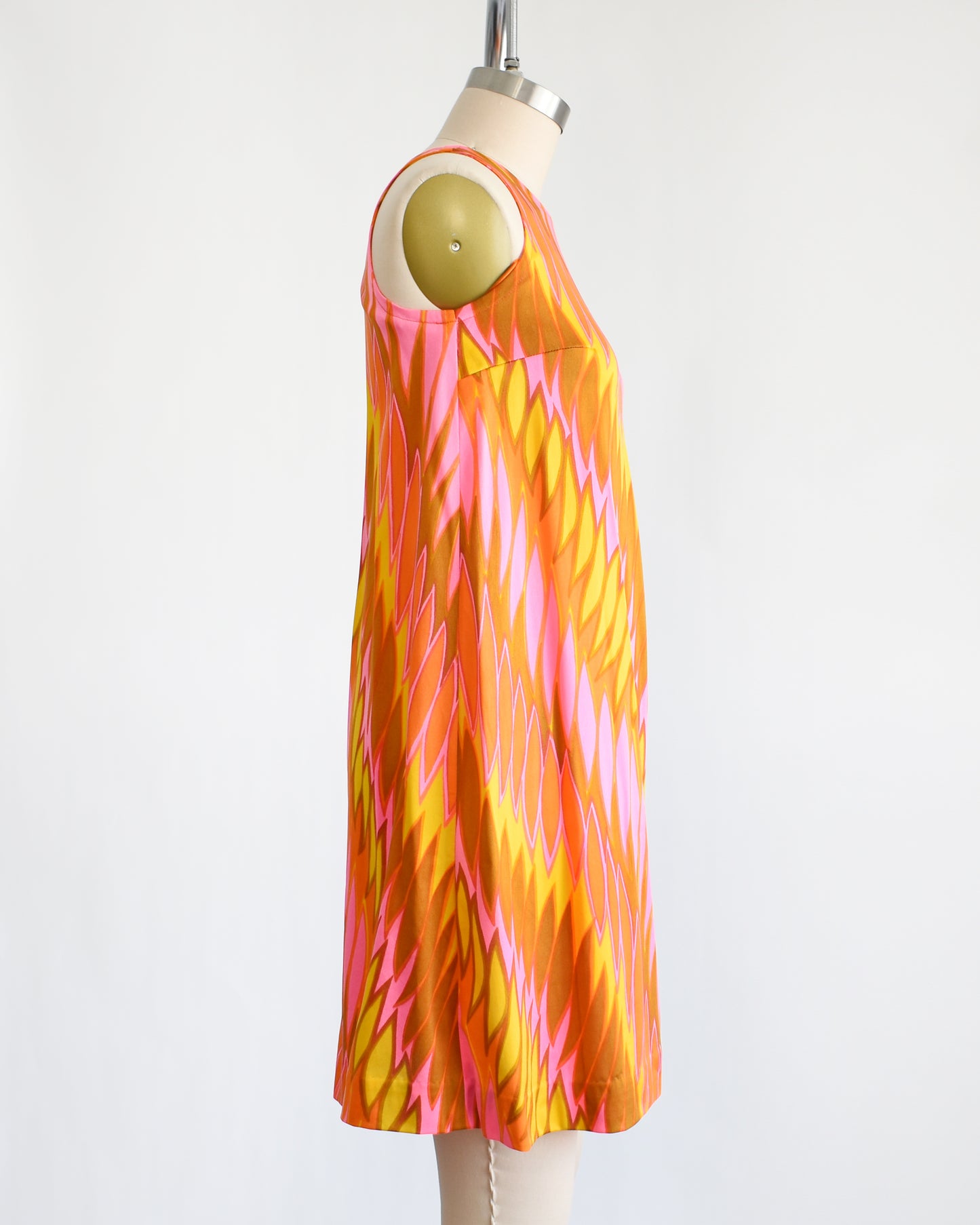 side view of a vintage 1960s mini dress that has a psychedelic print in orange, pink, yellow, and brown