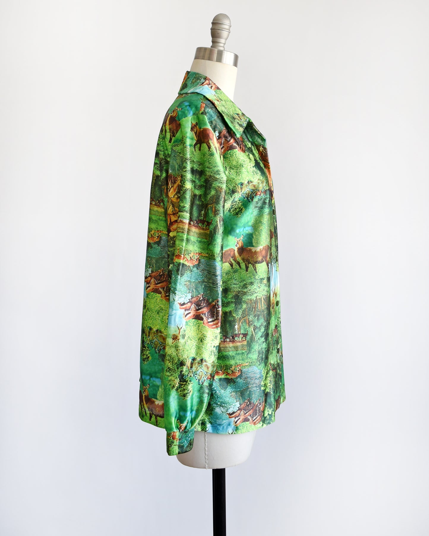 Side view of a vintage 70s green disco blouse that features a realistic photo print of different antelopes in different settings.