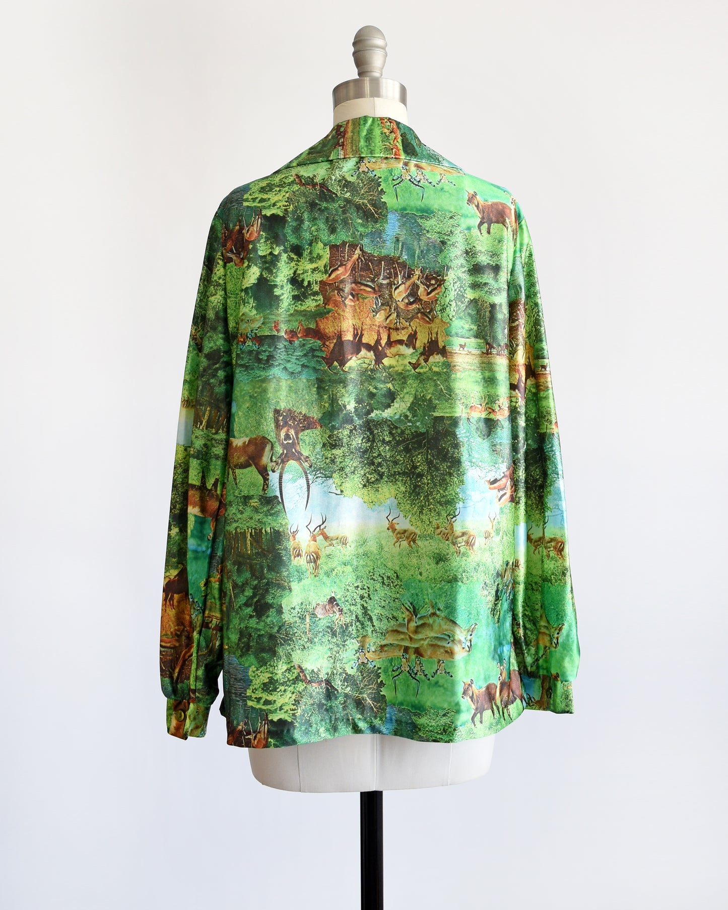 Back view of a vintage 70s green disco blouse that features a realistic photo print of different antelopes in different settings.