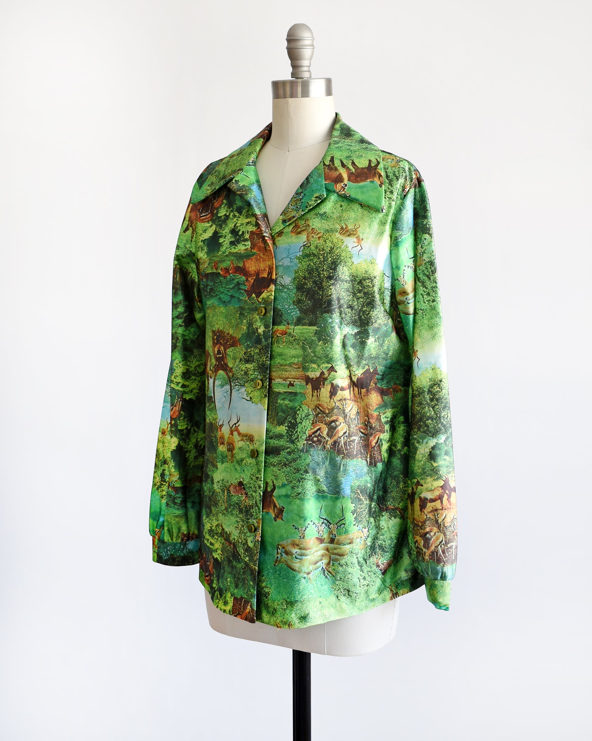 Side front view of a vintage 70s green disco blouse that features a realistic photo print of different antelopes in different settings.