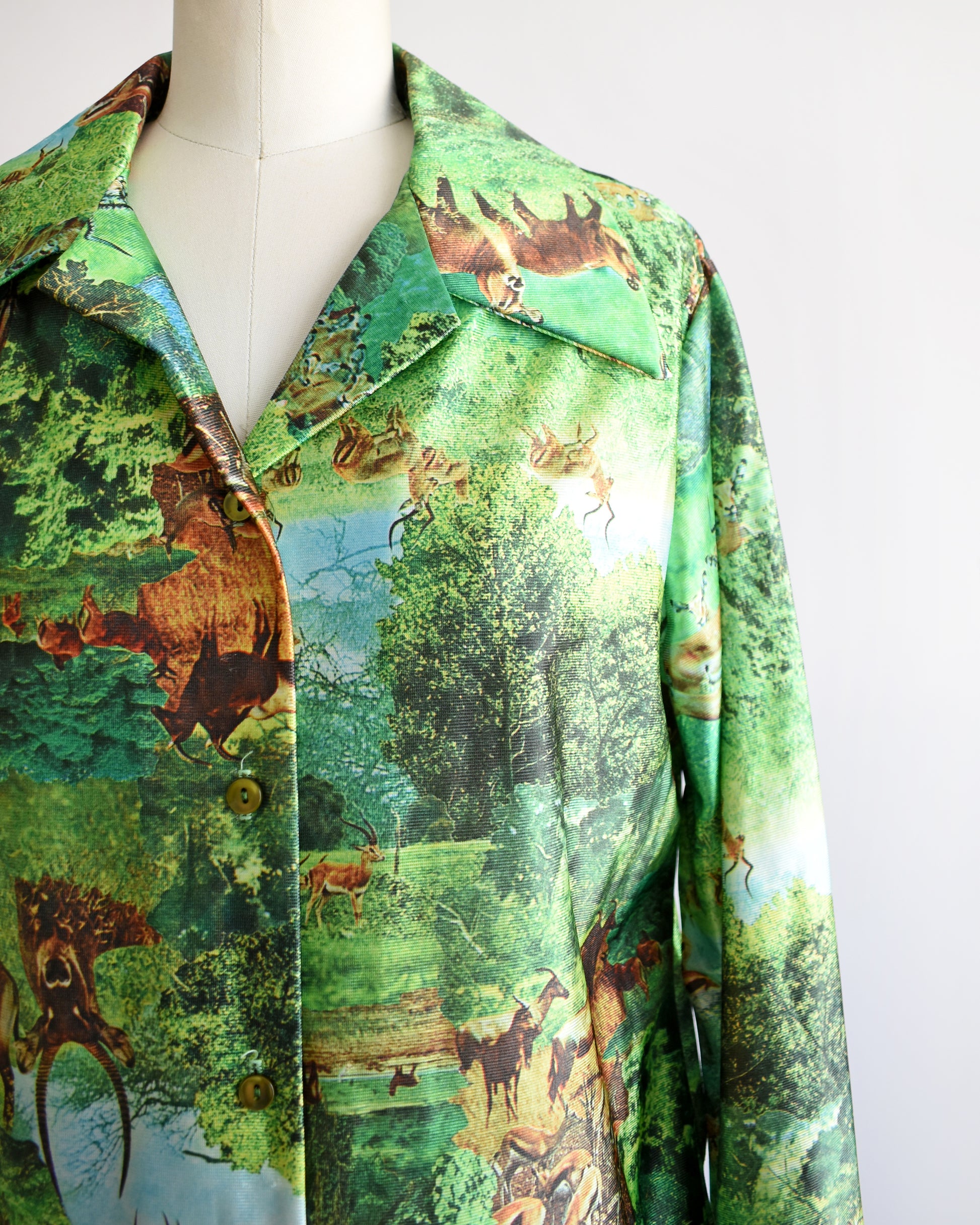 Close up of a vintage 70s green disco blouse that features a realistic photo print of different antelopes in different settings.