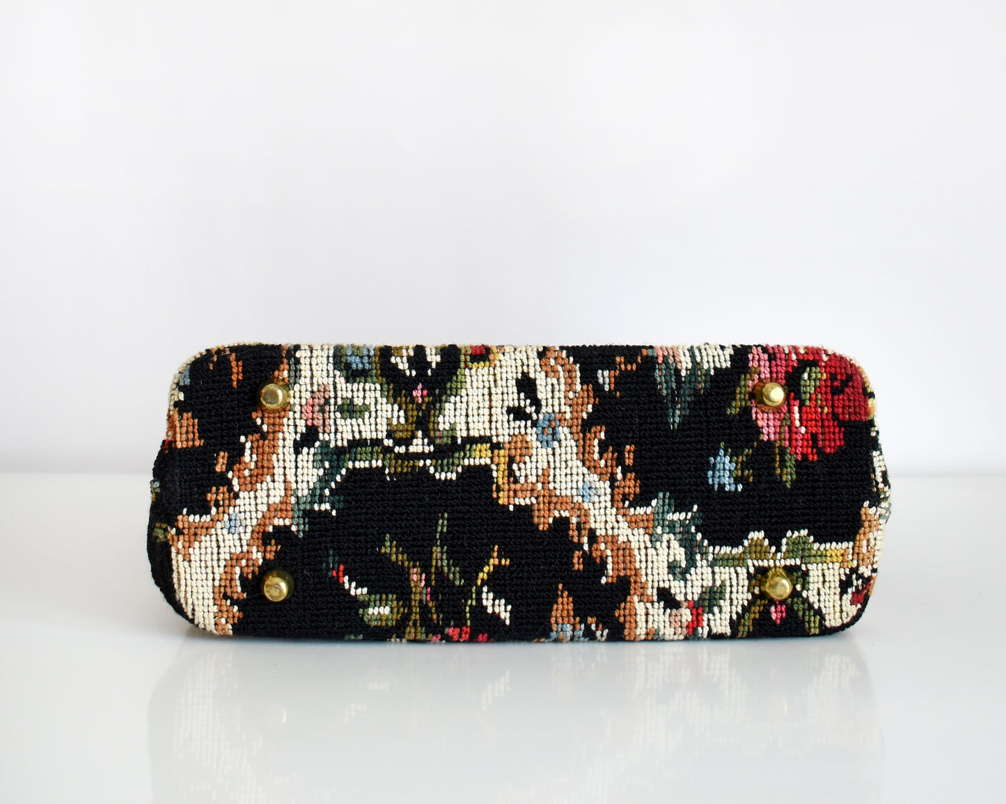 bottom view of 1960s floral needlepoint tapestry purse that has four gold tone feet