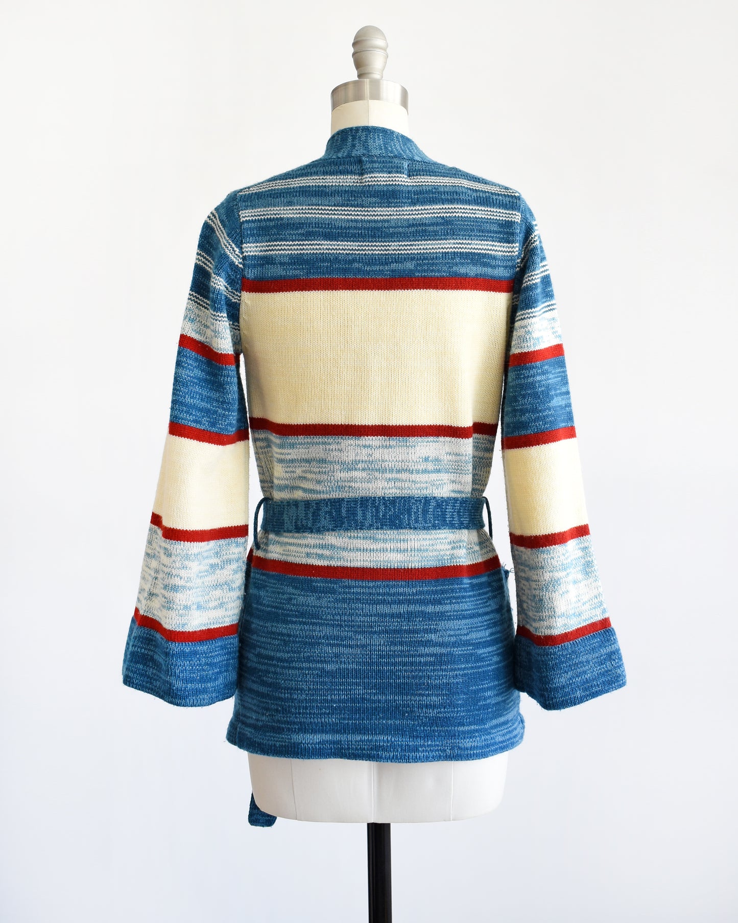 back view of a vintage 1970s blue floral space dye belted cardigan that has dark and light blue space dye knit with red and cream white stripes 