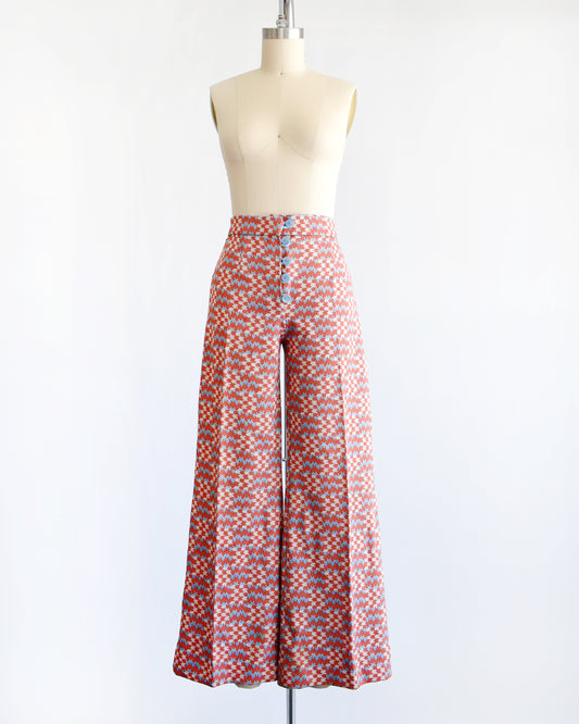  vintage 1970s wide leg pants feature a vibrant print with dark orange, white, and light blue arrows pointing in various directions down the legs.