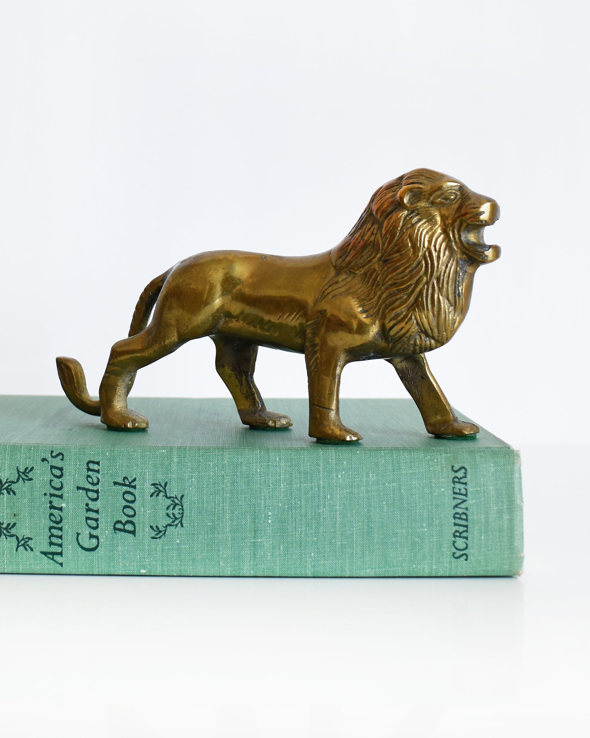a brass lion figurine standing on a book