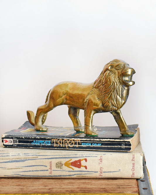 a brass lion figurine standing on books