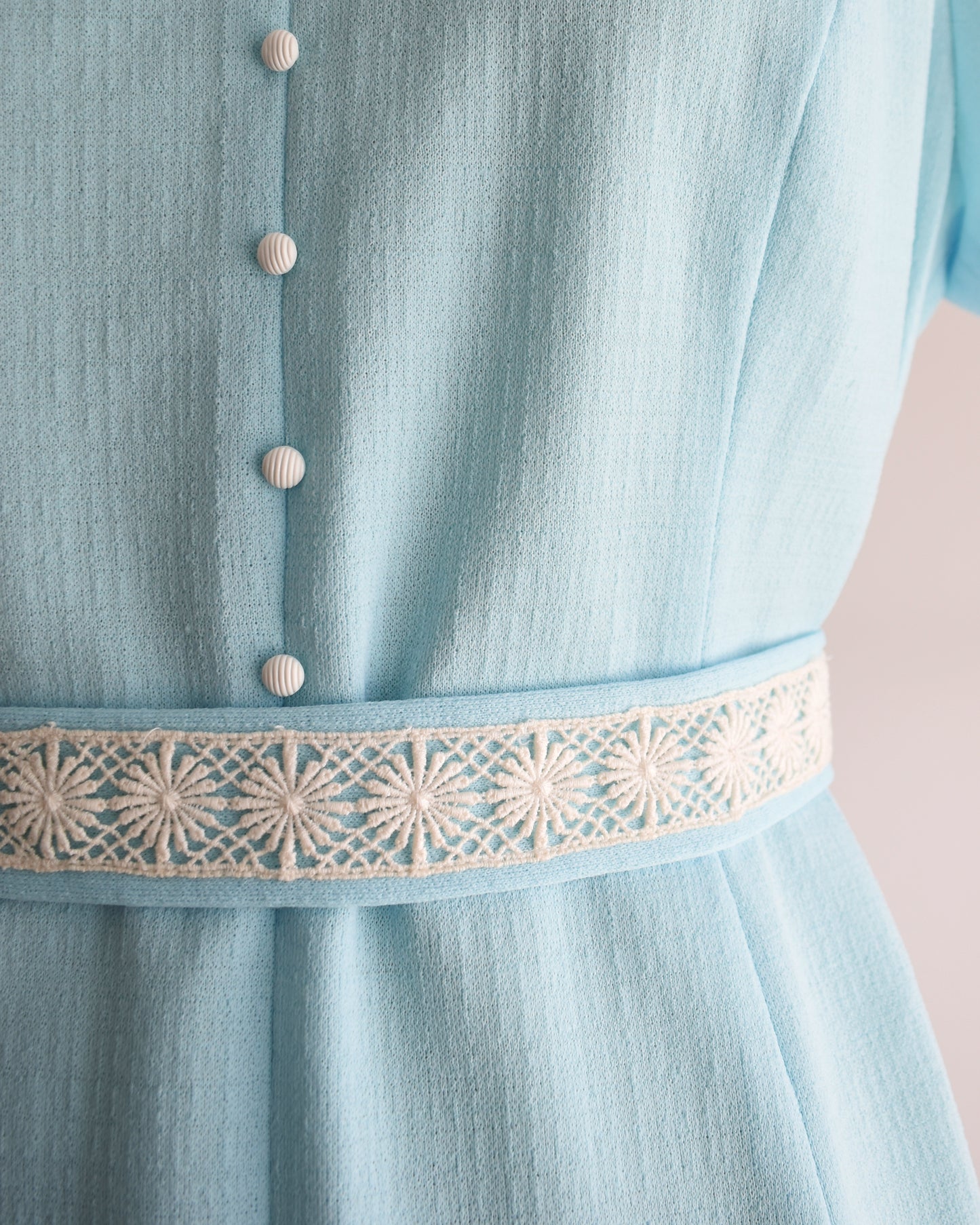 close up of the waist of the dress, which shows the buttons and lace trim belt