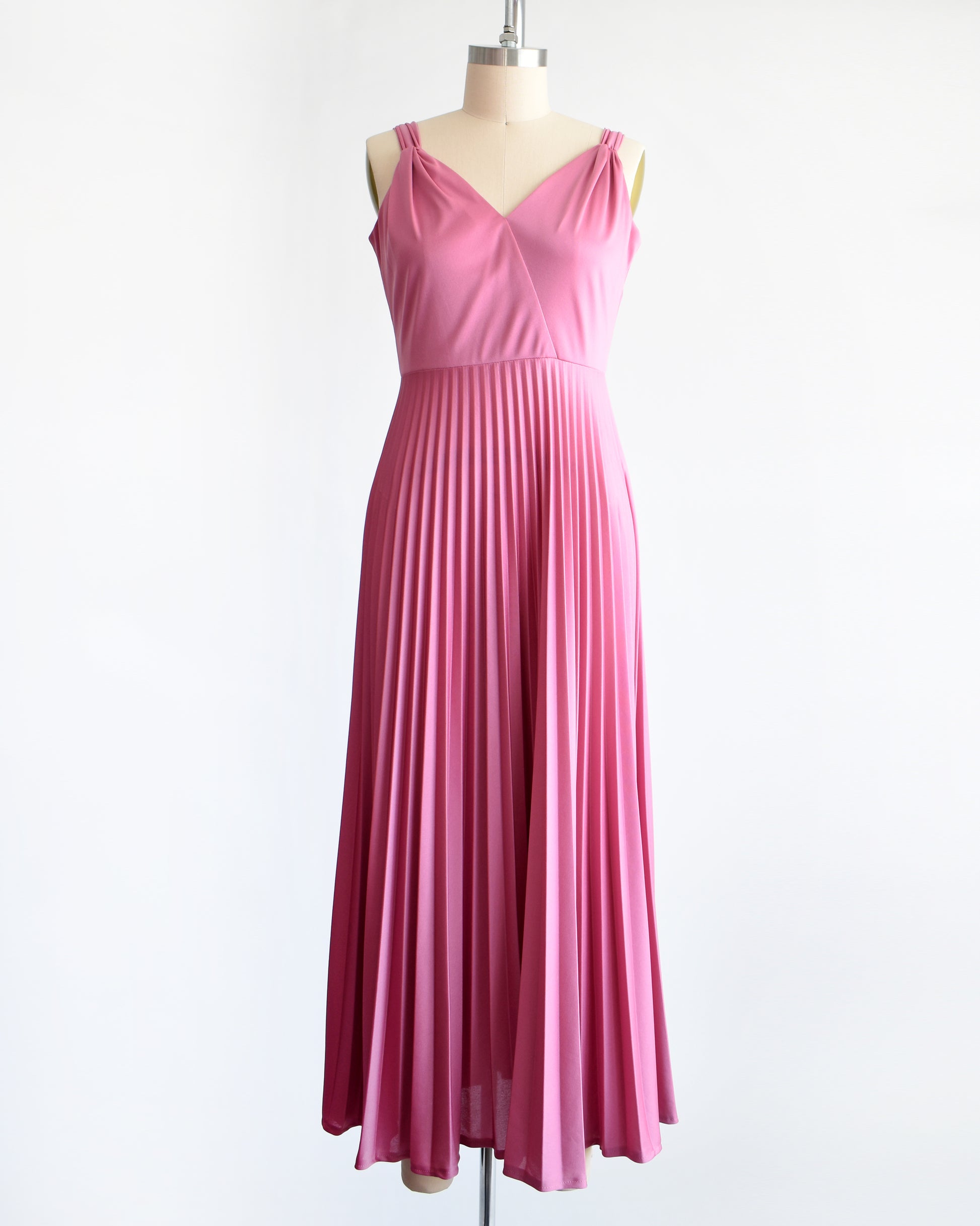 a vintage 1970s dusty pink disco maxi dress that has a faux wrap front, and a long accordion pleated maxi skirt.