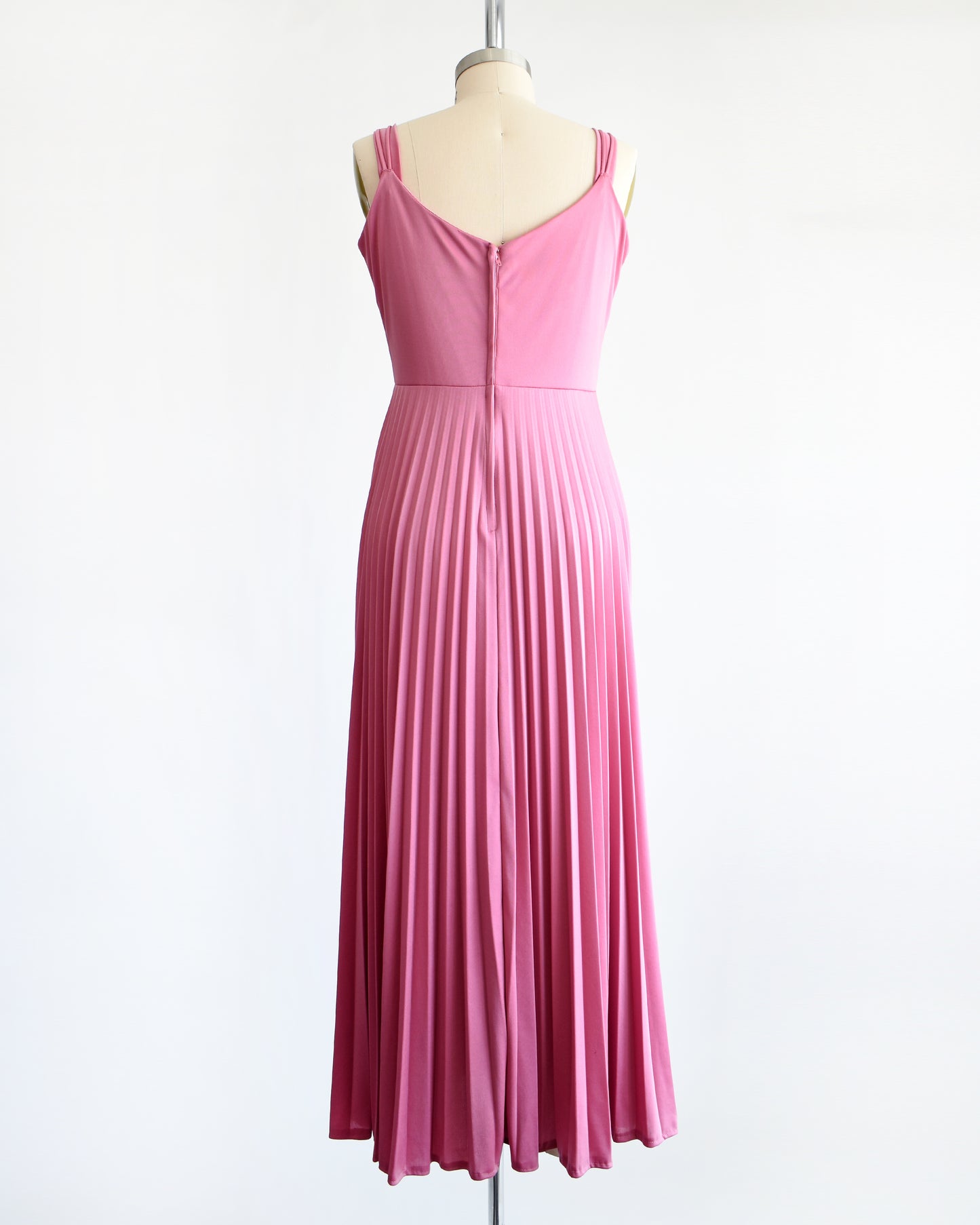 back view of a vintage 1970s dusty pink disco maxi dress that has a long accordion pleated maxi skirt.