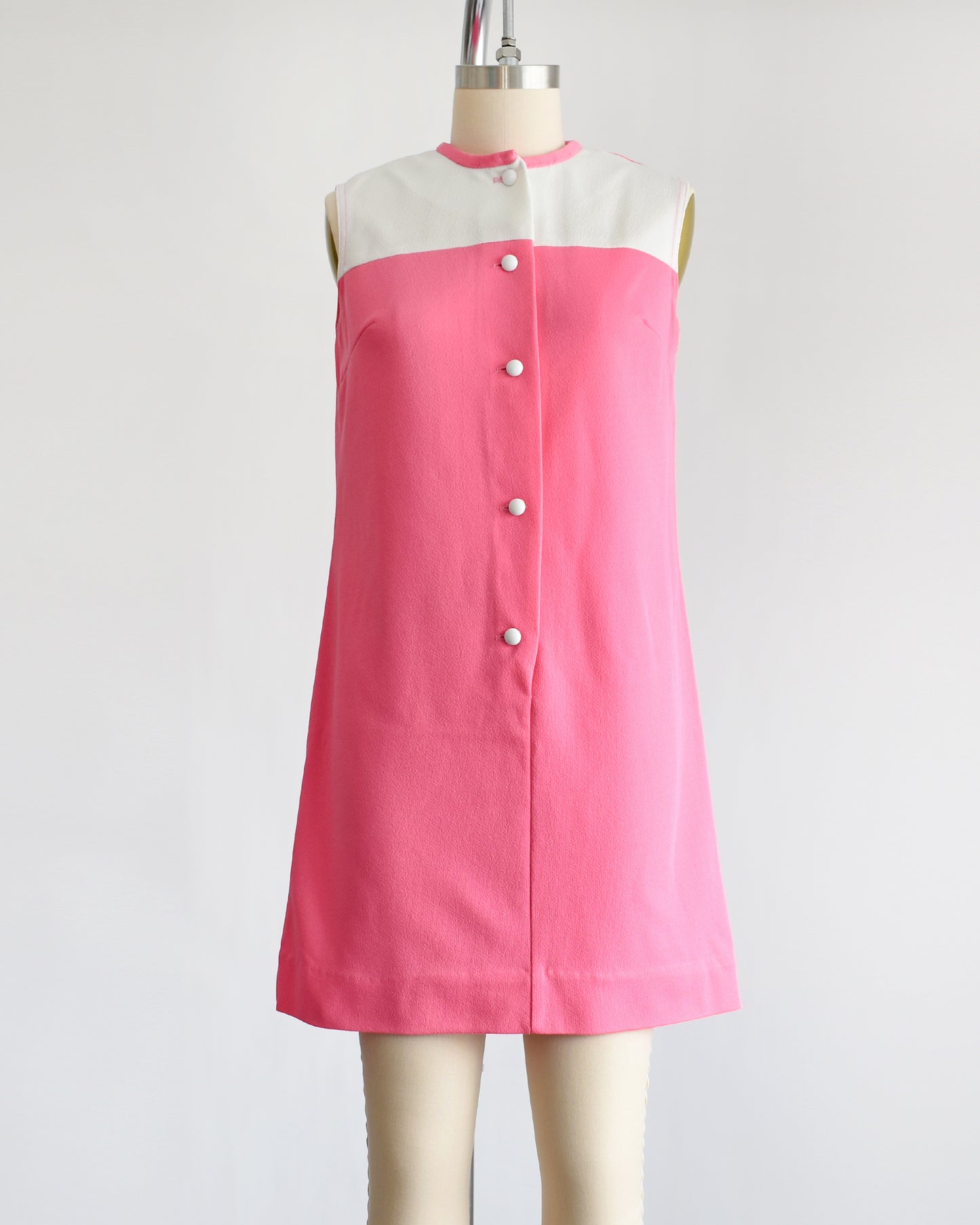 a vintage 1960s pink and white mod mini dress that has five white buttons down the front.