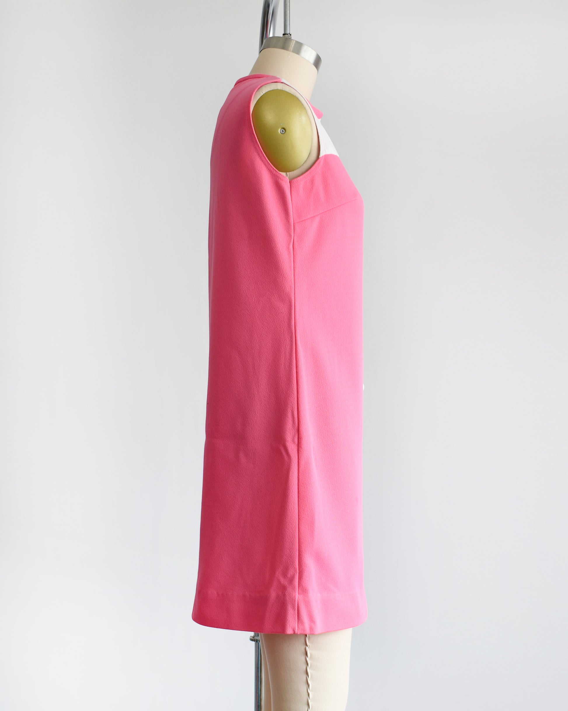 side view of a vintage 1960s pink and white mod mini dress that has five white buttons down the front.