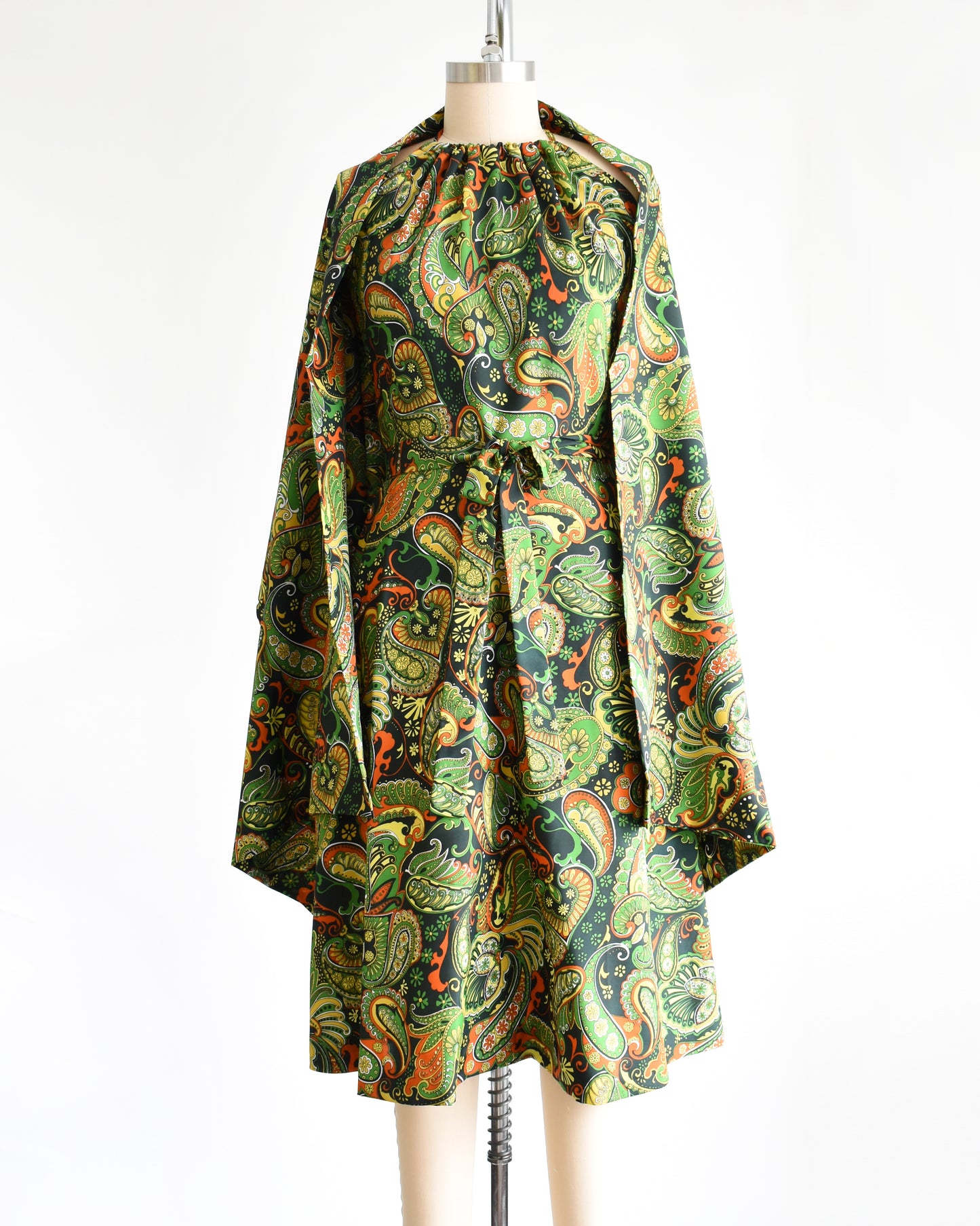 A vintage 1970s psychedelic paisley dress with matching shawl on a mannequin against a white background