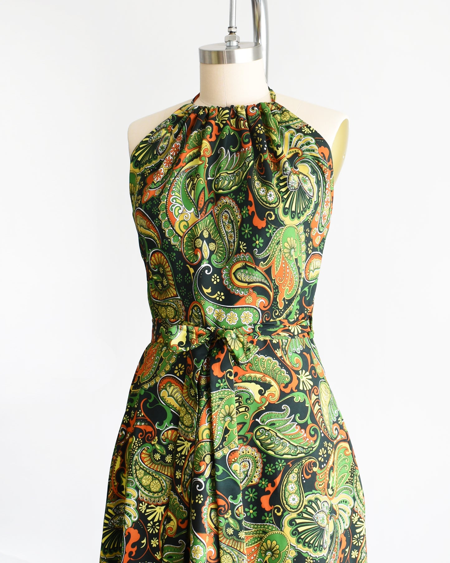 side front view of a vintage 1970s psychedelic paisley dress on a mannequin against a white background